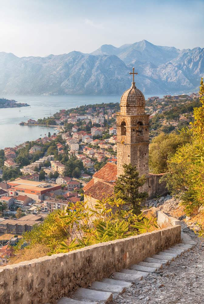 Kirchturm in Kotor, Montenegro, mit Blick auf die Bucht und Berge.