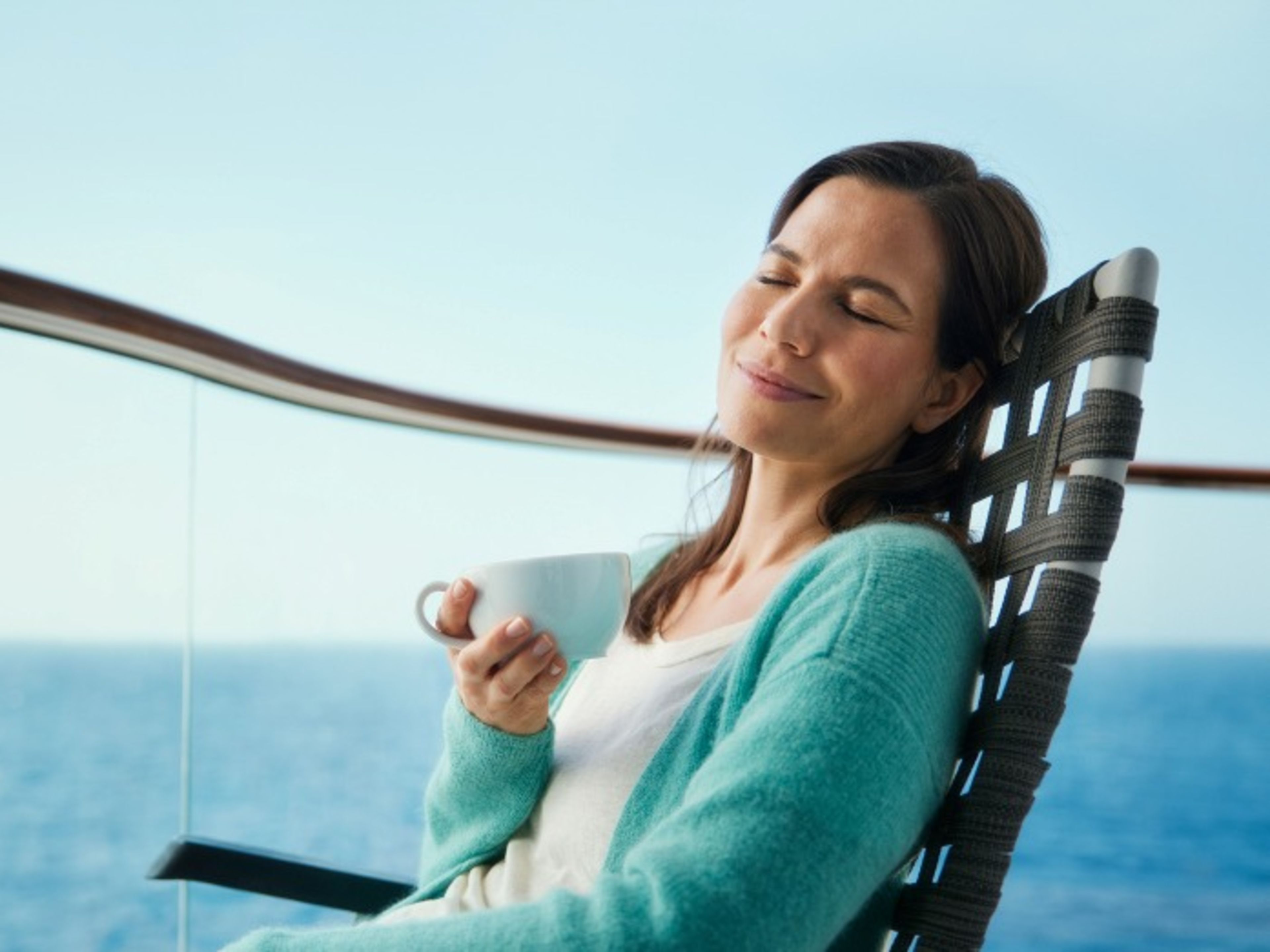 Frau entspannt mit Tasse auf Kreuzfahrtschiff, Meerblick. Frau entspannt mit Tasse auf Kreuzfahrtschiff, Meerblick.