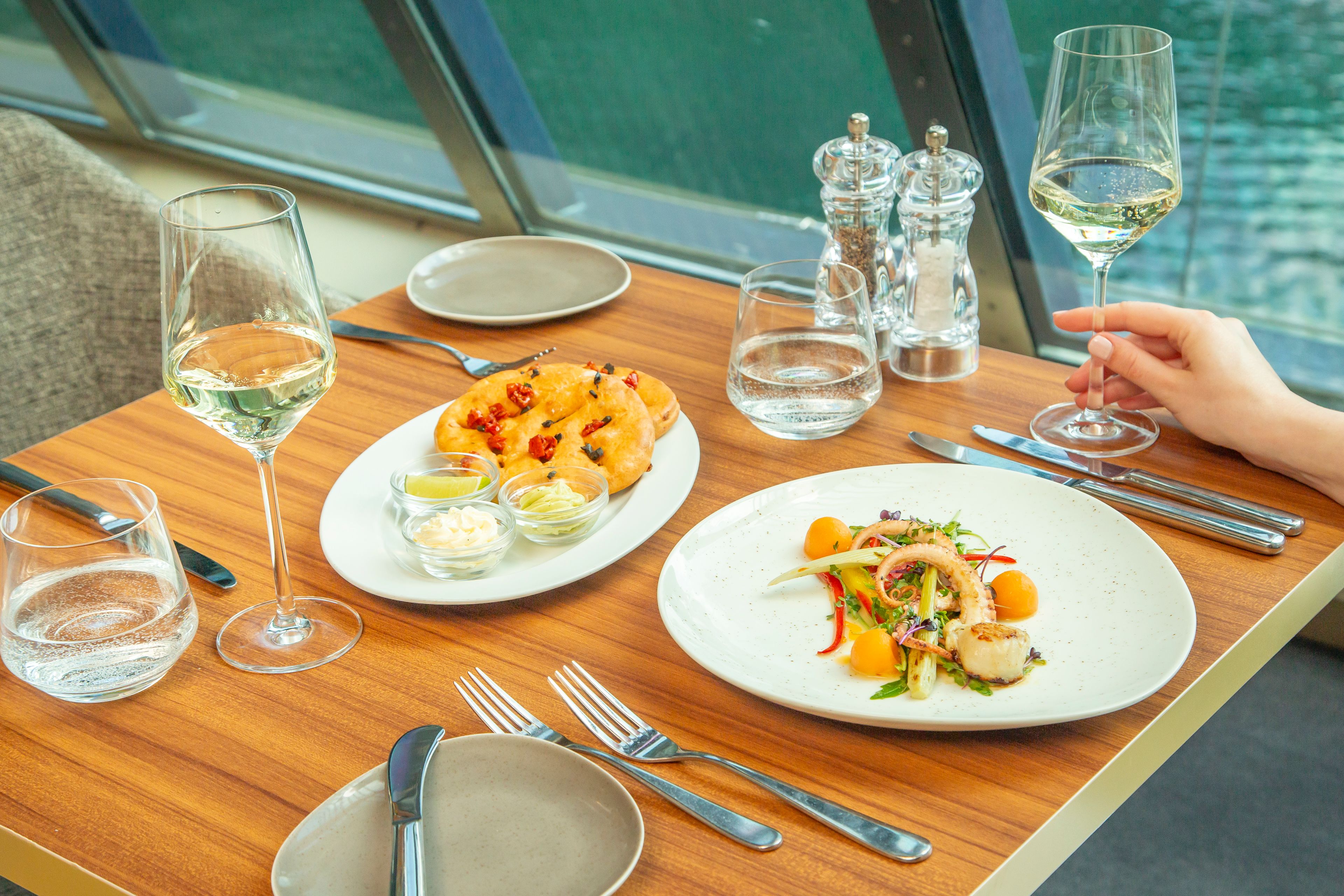 Gedeckter Tisch mit Meeresfrüchtesalat, Brot und Weißwein.