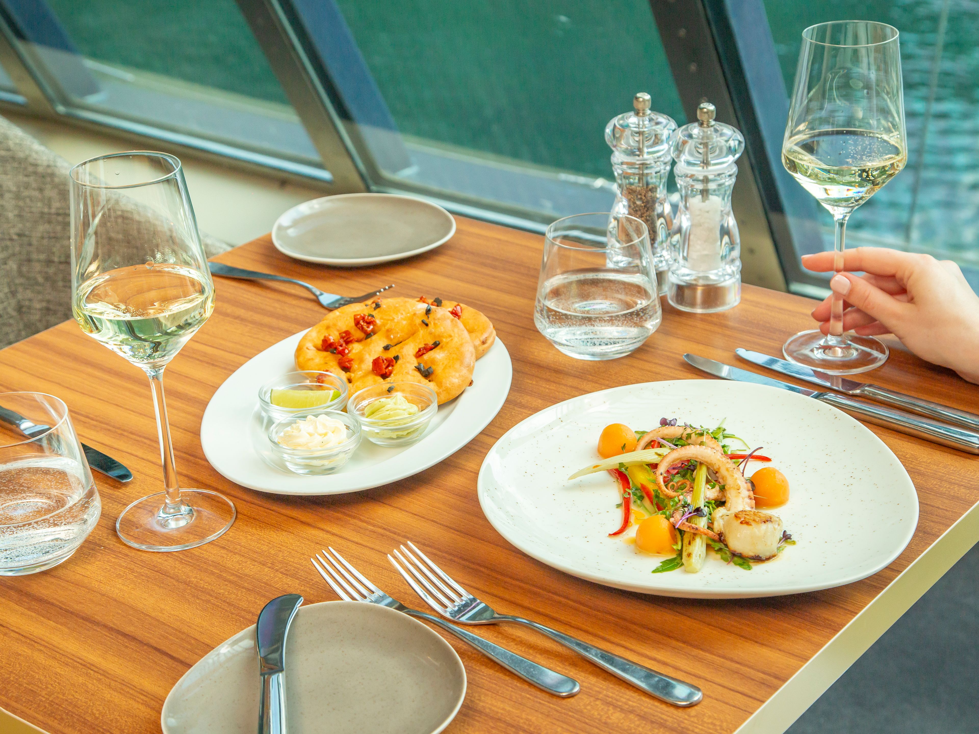 Gedeckter Tisch mit Meeresfrüchtesalat, Brot und Weißwein. Gedeckter Tisch mit Meeresfrüchtesalat, Brot und Weißwein.