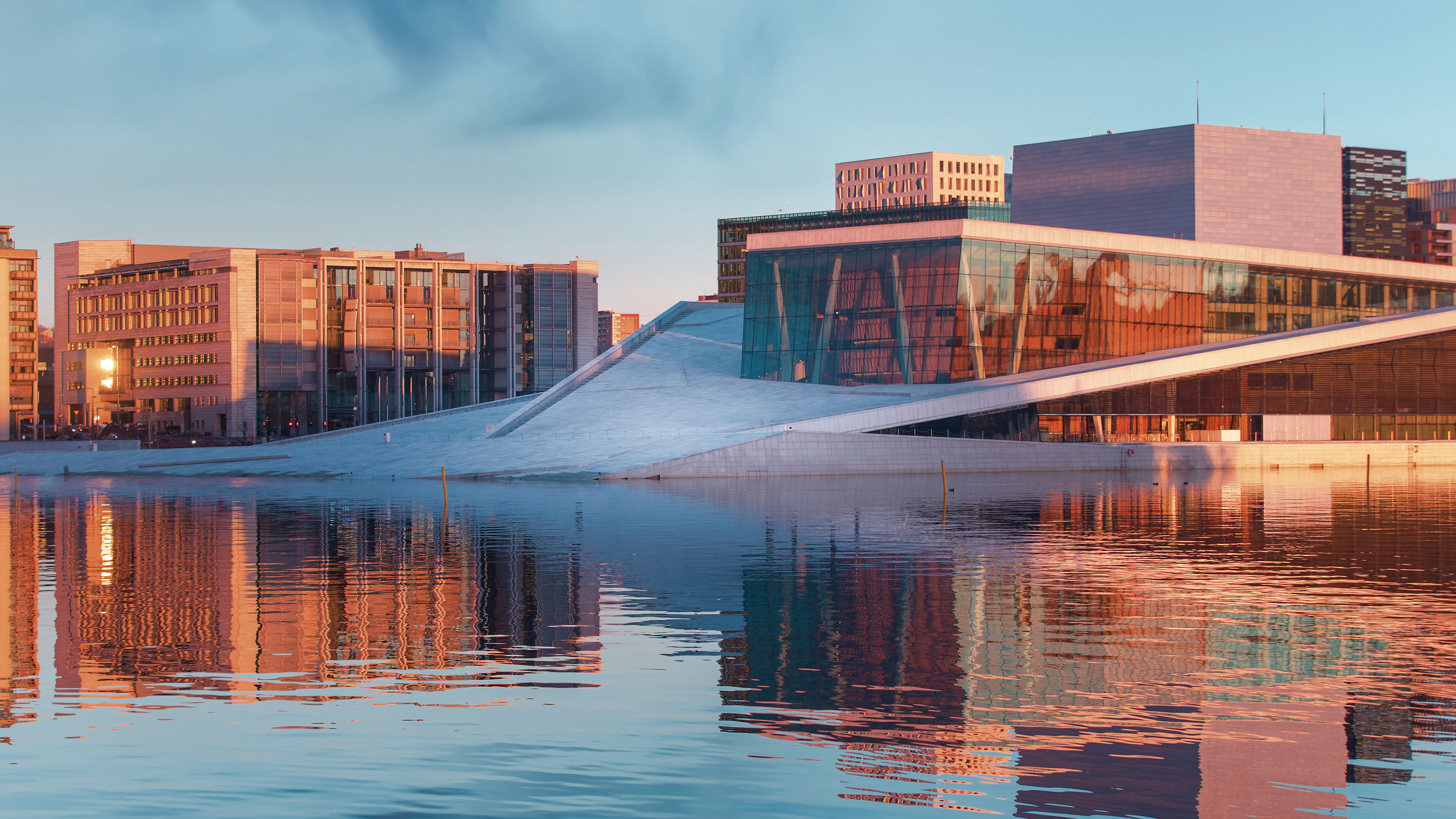 Opernhaus Oslo bei Sonnenuntergang, reflektiert im Wasser.