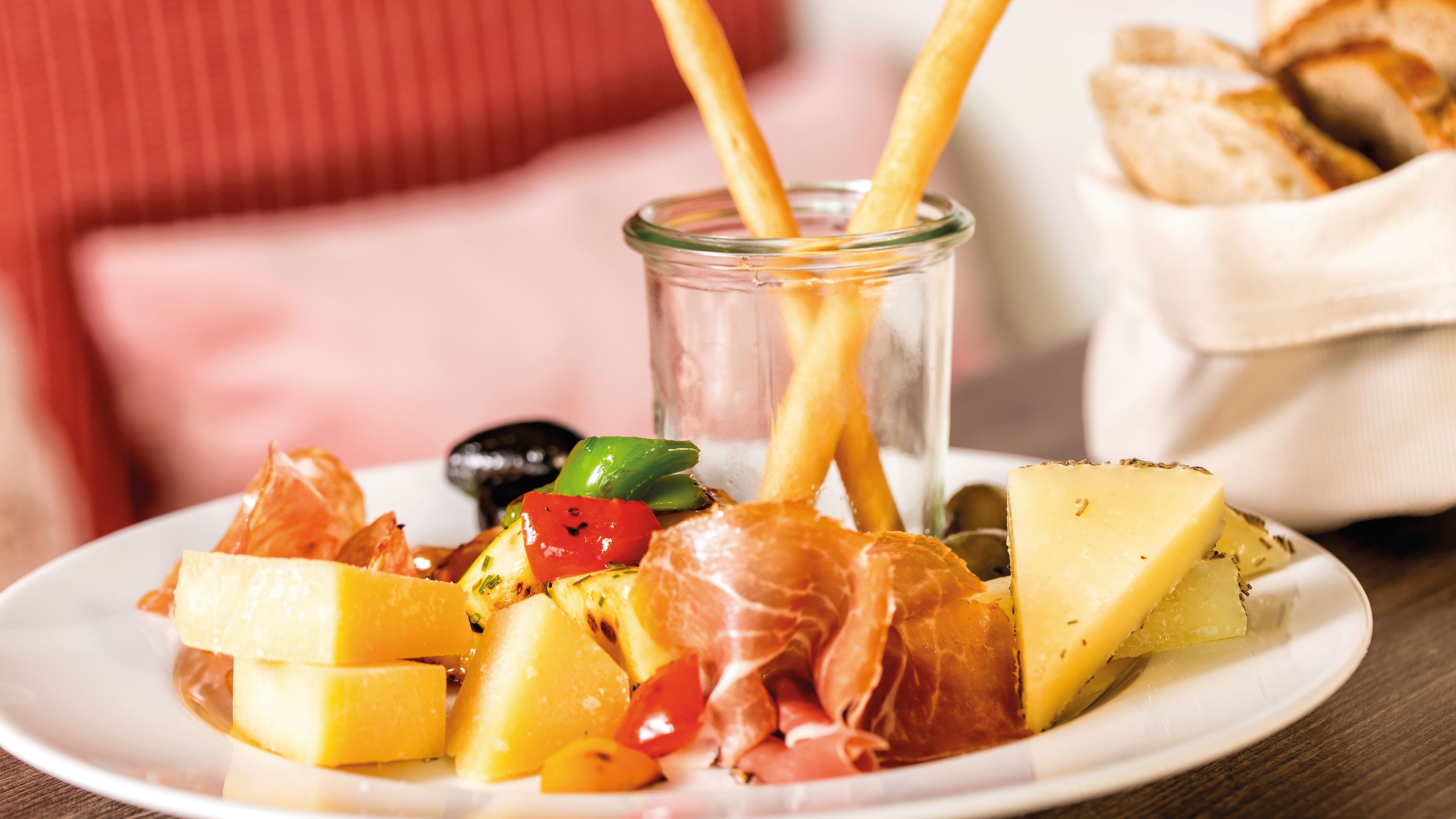 Käse, Schinken, Oliven und Brotstangen auf weißem Teller. Käse, Schinken, Oliven und Brotstangen auf weißem Teller.
