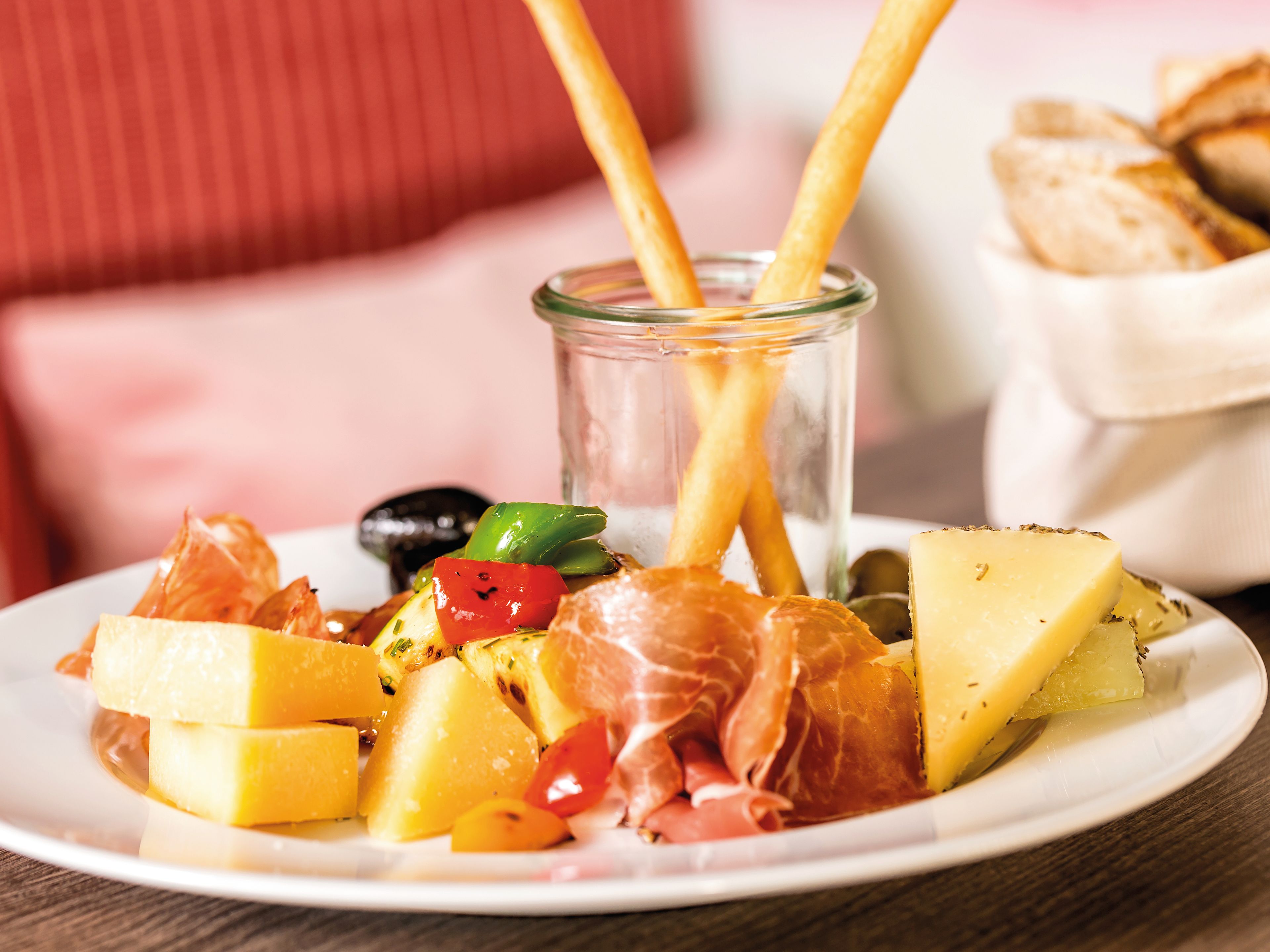 Käse, Schinken, Oliven und Brotstangen auf weißem Teller. Käse, Schinken, Oliven und Brotstangen auf weißem Teller.