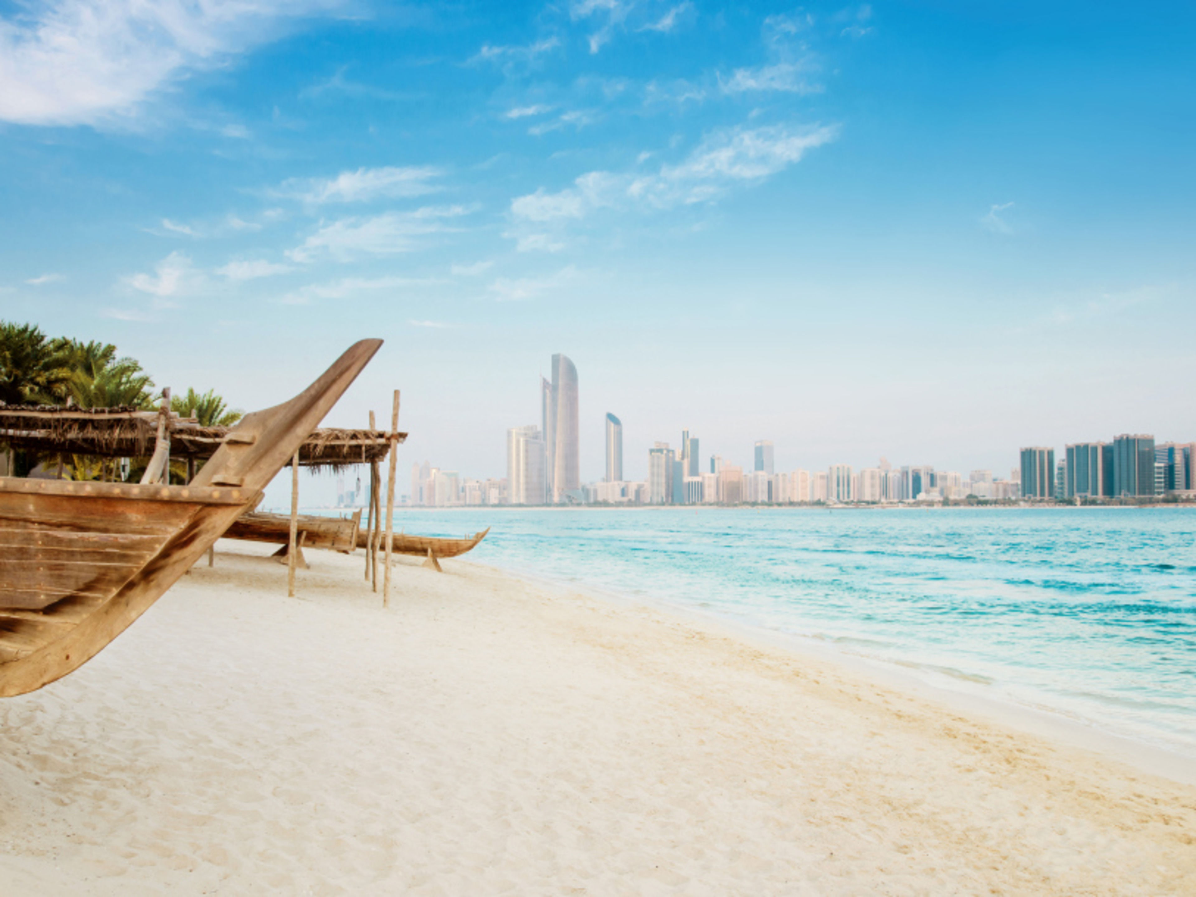 Strand mit traditionellen Booten und Skyline von Abu Dhabi. Strand mit traditionellen Booten und Skyline von Abu Dhabi.