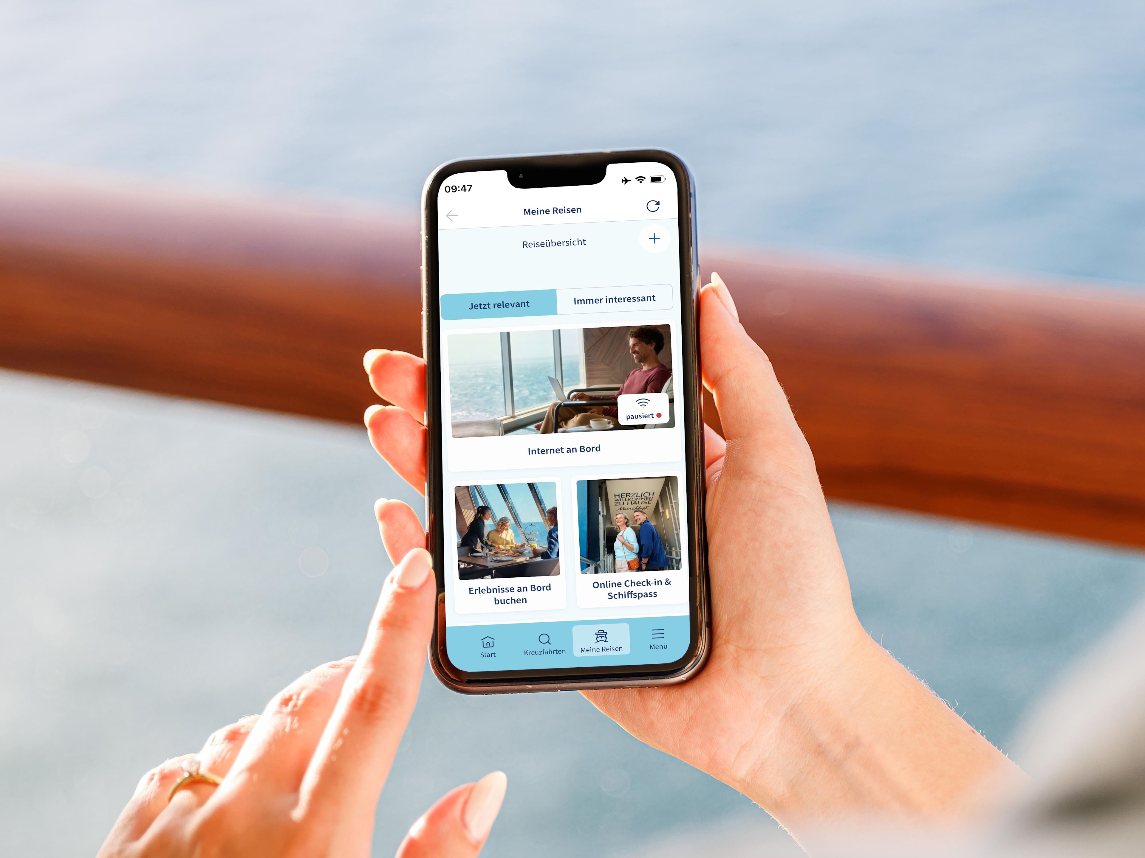 Person hält Smartphone mit Kreuzfahrt-App, Meer im Hintergrund. Person hält Smartphone mit Kreuzfahrt-App, Meer im Hintergrund.