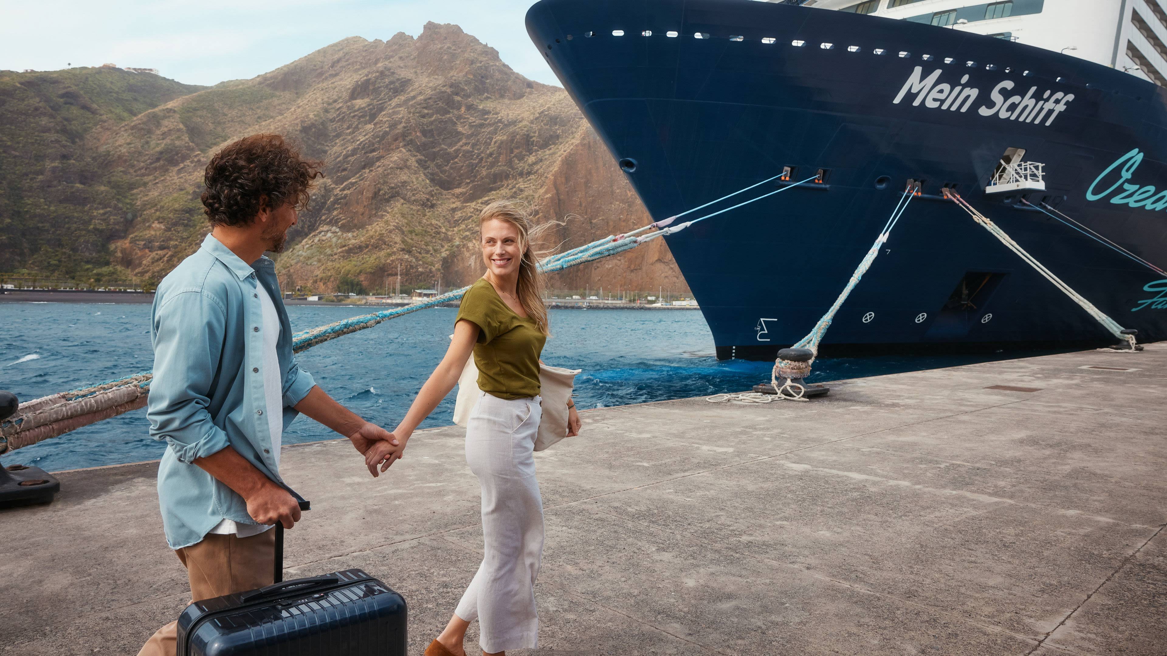 Paar am Hafen vor Kreuzfahrtschiff der Mein Schiff® Flotte, Berge im Hintergrund. Paar am Hafen vor Kreuzfahrtschiff der Mein Schiff® Flotte, Berge im Hintergrund.