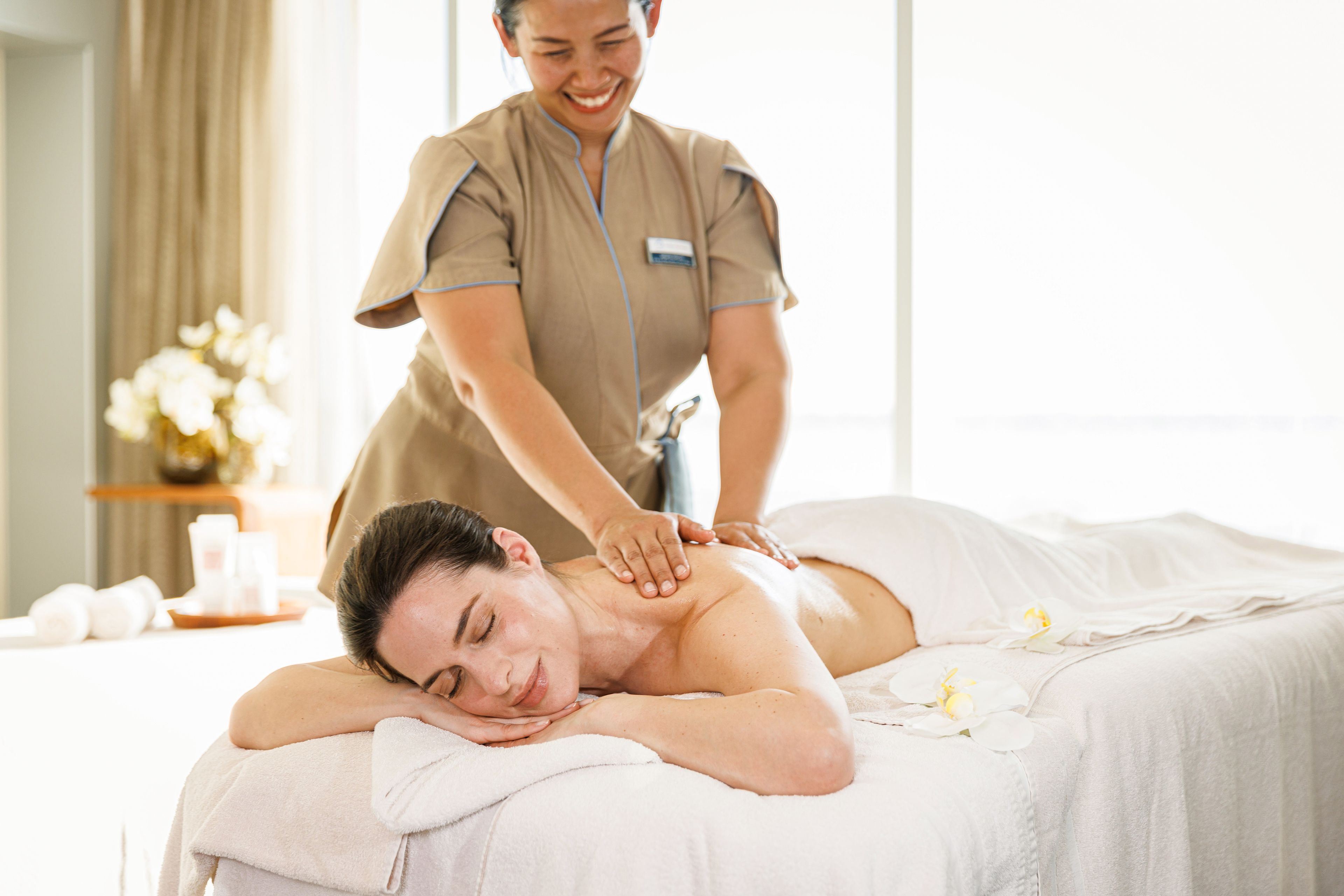Frau genießt entspannende Massage in hellem Spa-Raum.