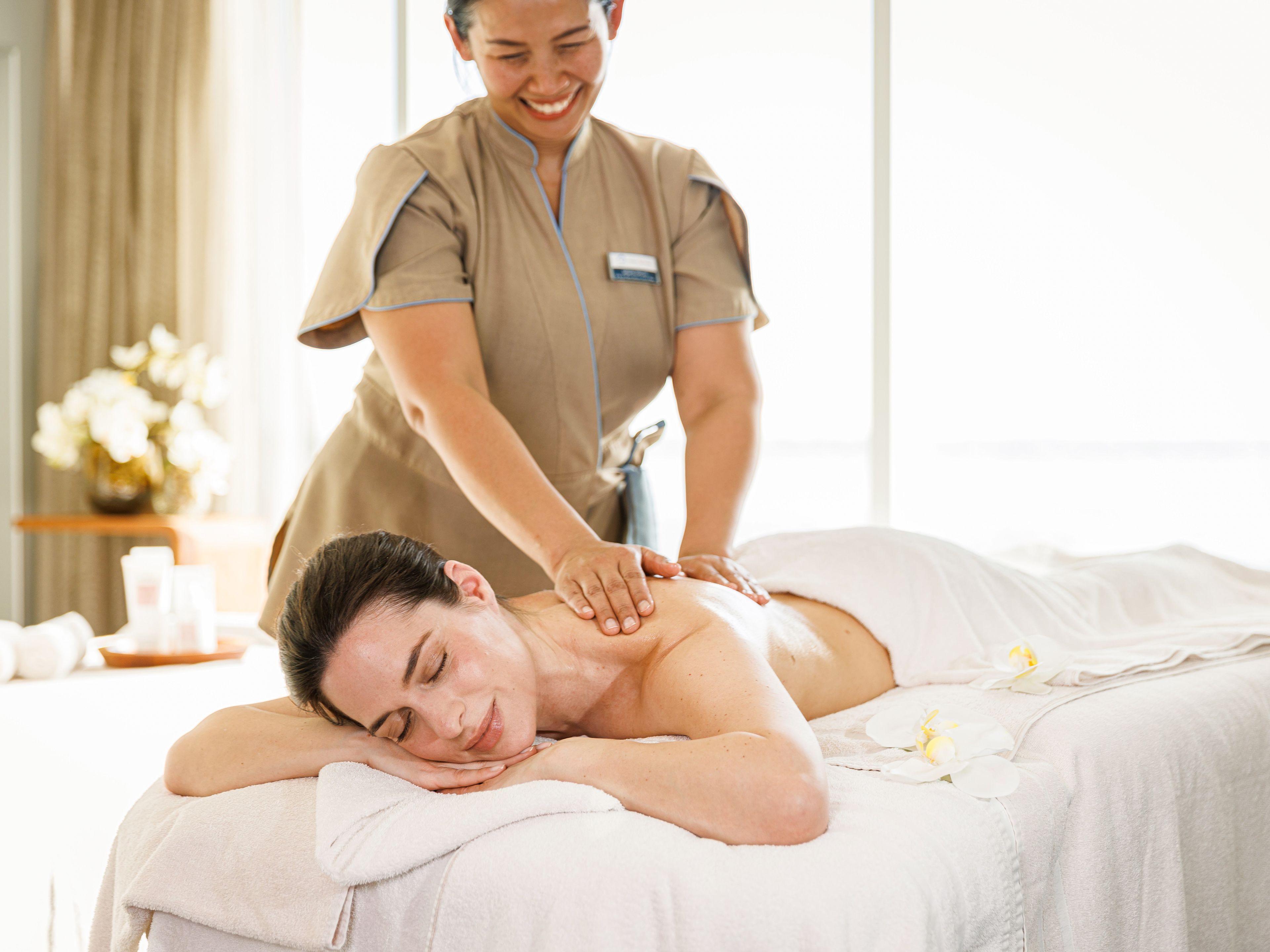 Frau genießt entspannende Massage in hellem Spa-Raum. Frau genießt entspannende Massage in hellem Spa-Raum.