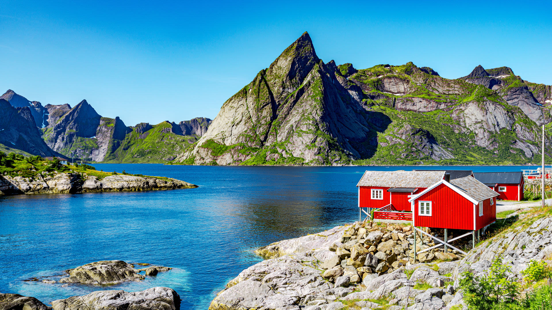 Rote Hütten am Fjord vor steilen Bergen, Lofoten.