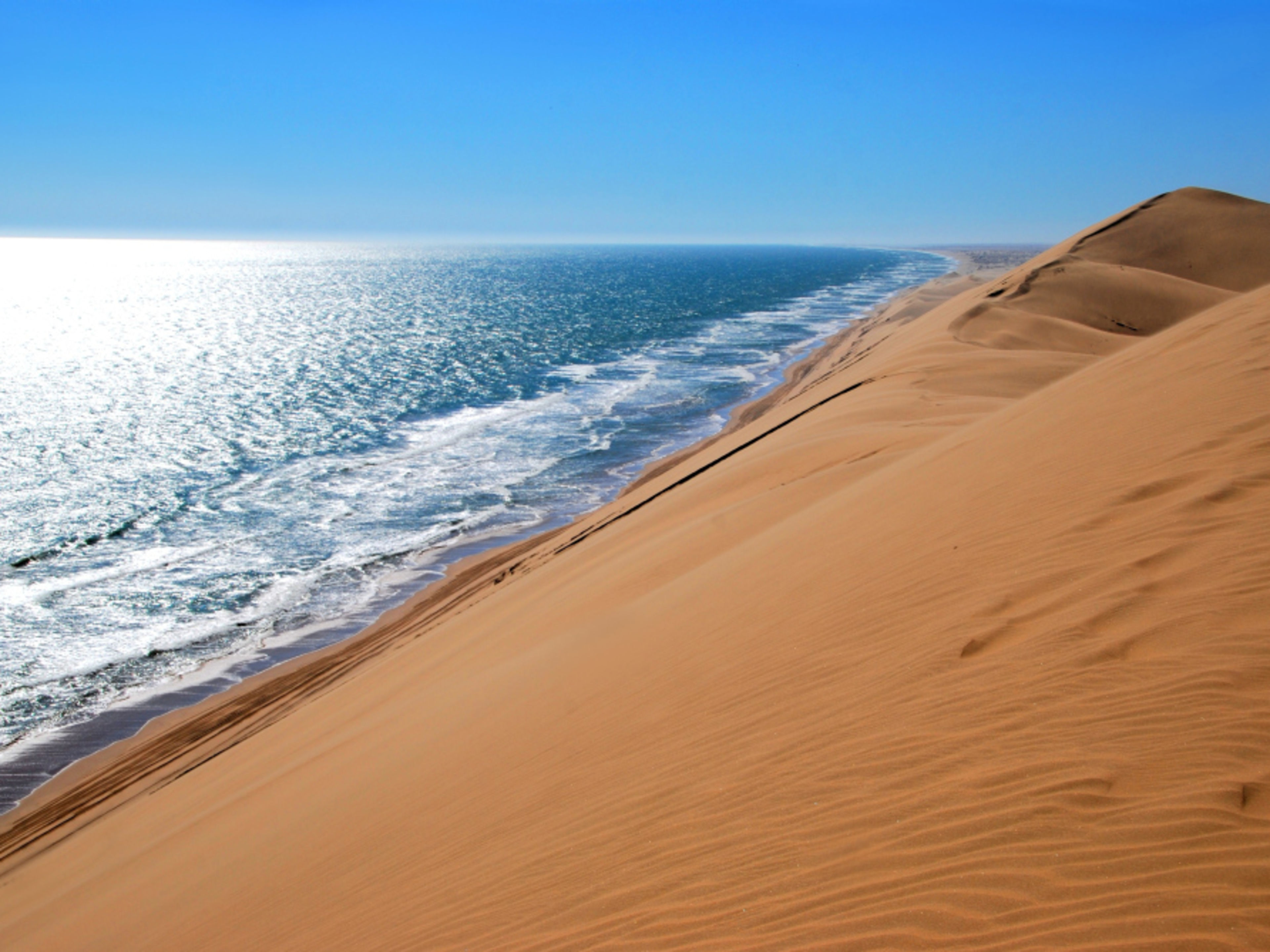 Sanddünen treffen auf das Meer unter blauem Himmel. Sanddünen treffen auf das Meer unter blauem Himmel.