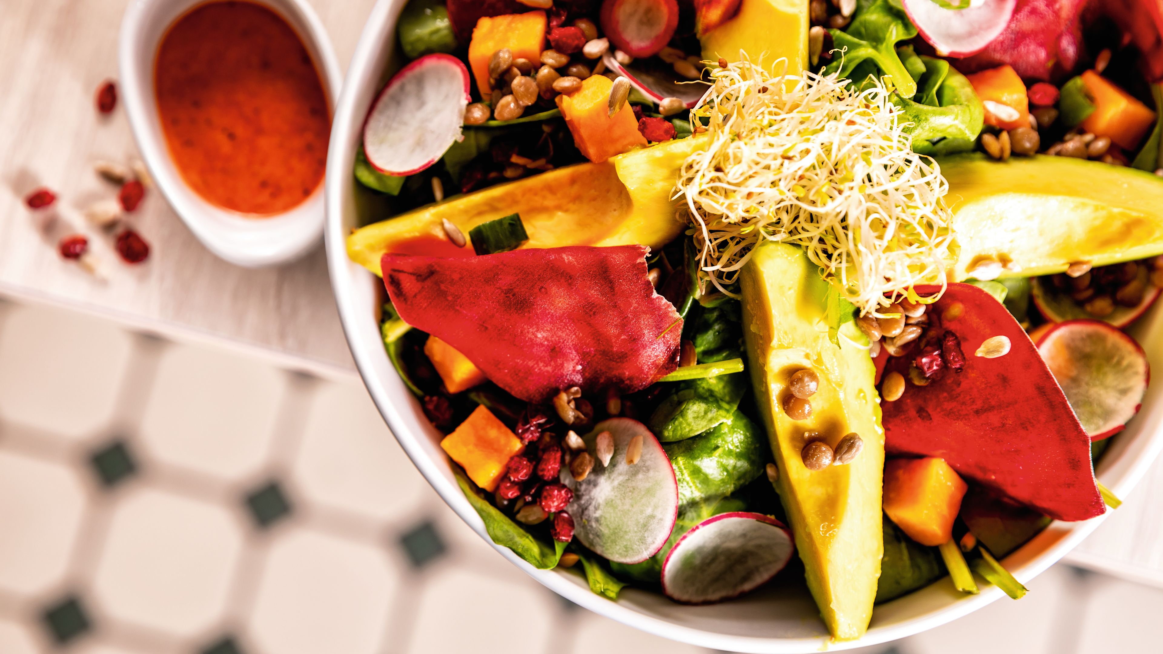 Bunter Salat mit Avocado, Rote Bete, Radieschen und Sprossen in weißer Schüssel. Bunter Salat mit Avocado, Rote Bete, Radieschen und Sprossen in weißer Schüssel.