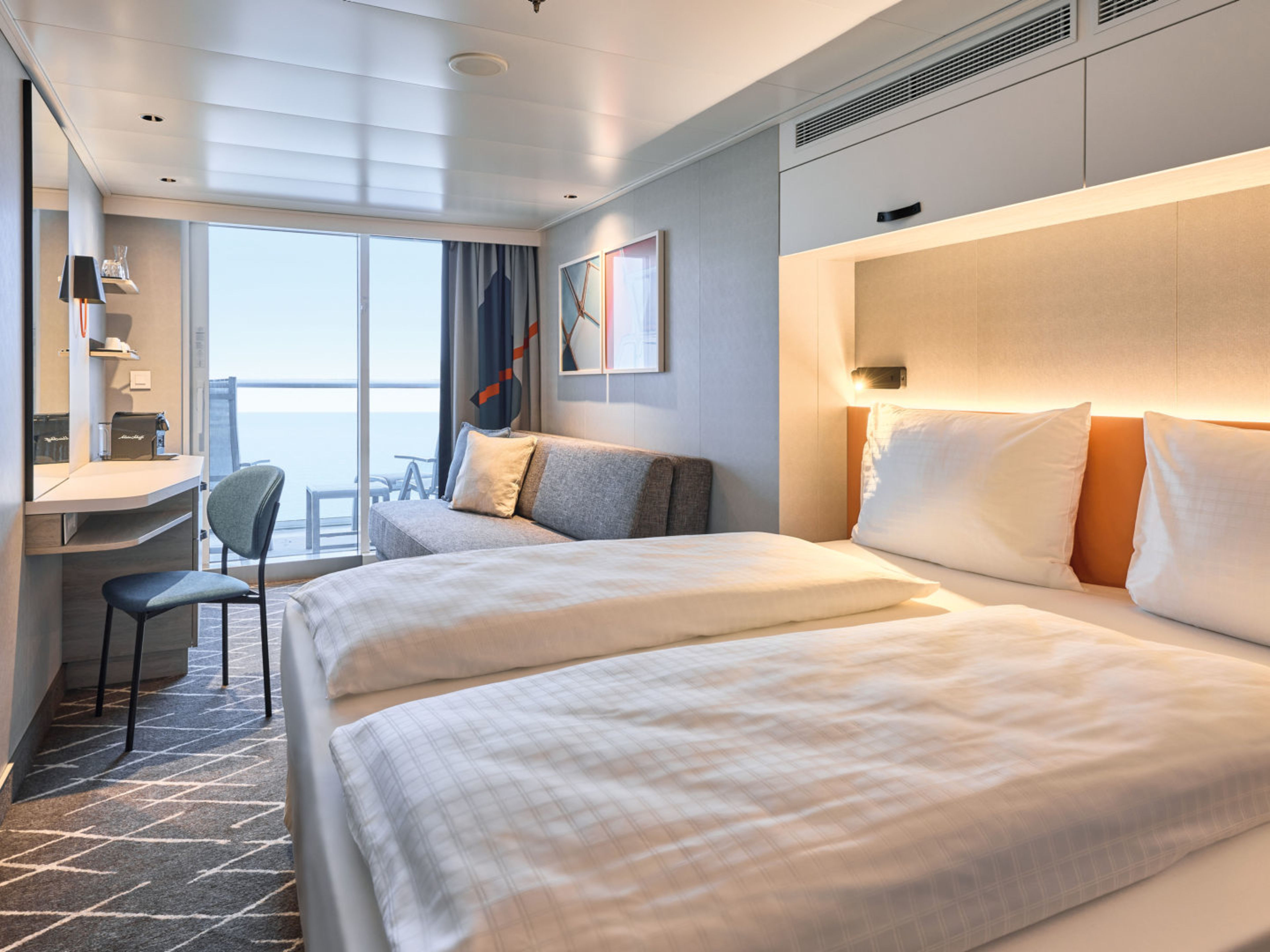 Helles Kreuzfahrtschiff-Kabine mit Doppelbett, Sofa und Balkon. Helles Kreuzfahrtschiff-Kabine mit Doppelbett, Sofa und Balkon.