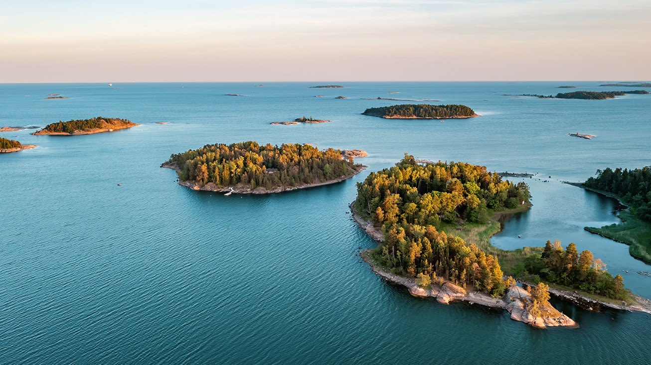 Inseln im Archipel, umgeben von blauem Meer, Sonnenuntergang.