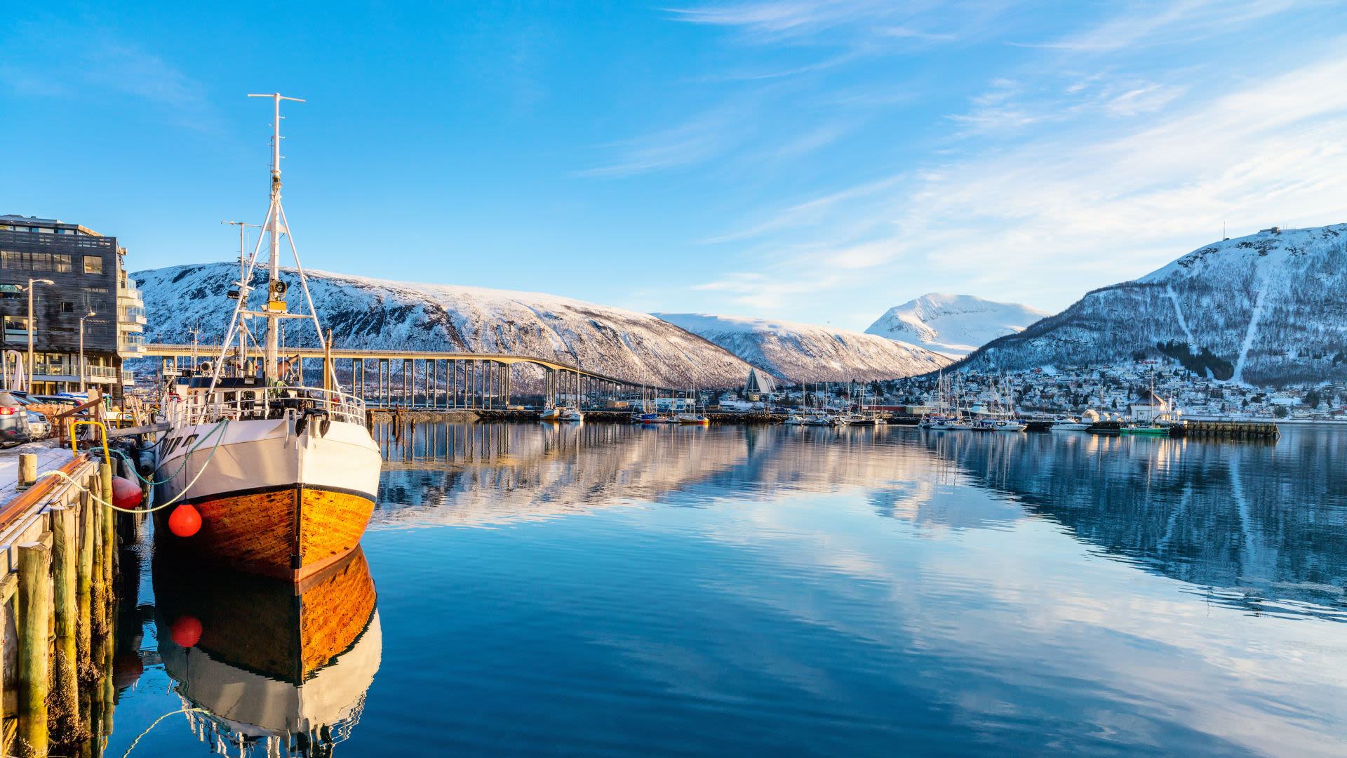 Holzboot im Hafen von Tromsø, Norwegen, mit schneebedeckten Bergen im Hintergrund. Holzboot im Hafen von Tromsø, Norwegen, mit schneebedeckten Bergen im Hintergrund.