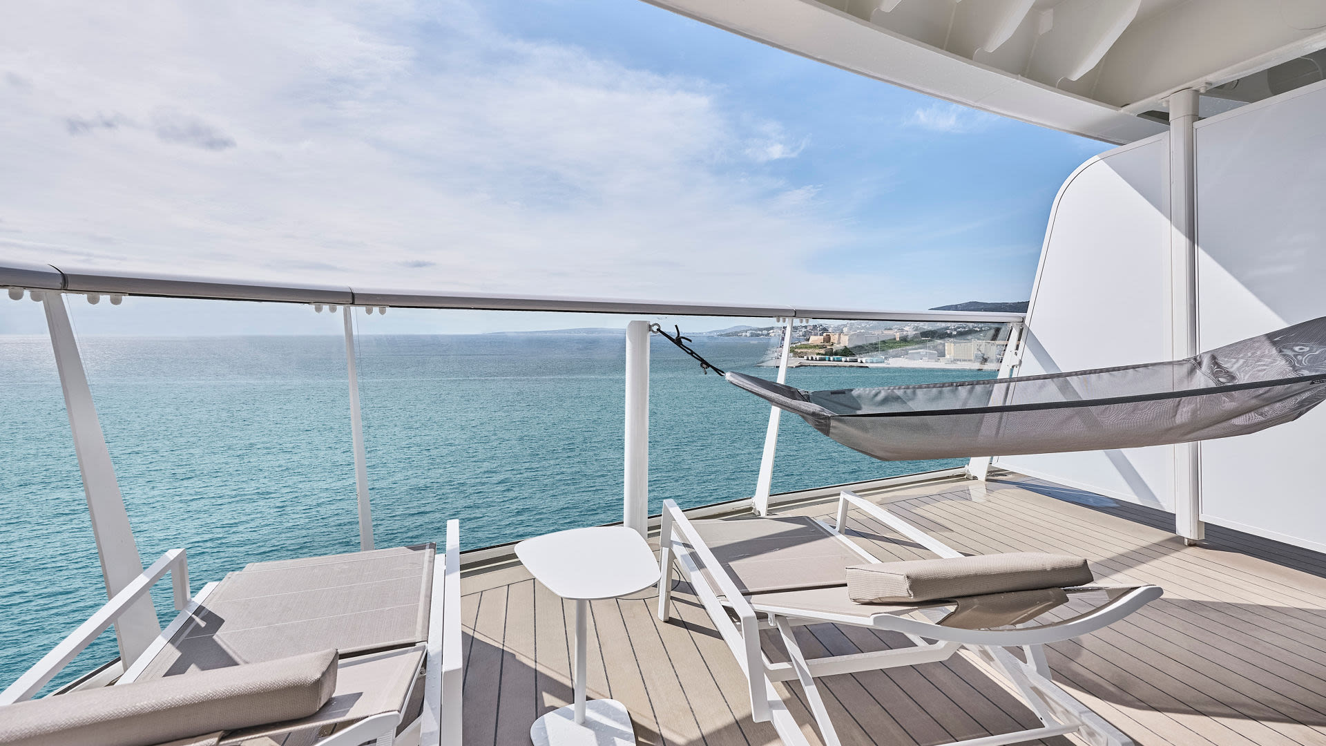 Balkon mit Liegestühlen und Hängematte auf Kreuzfahrtschiff, Meerblick.