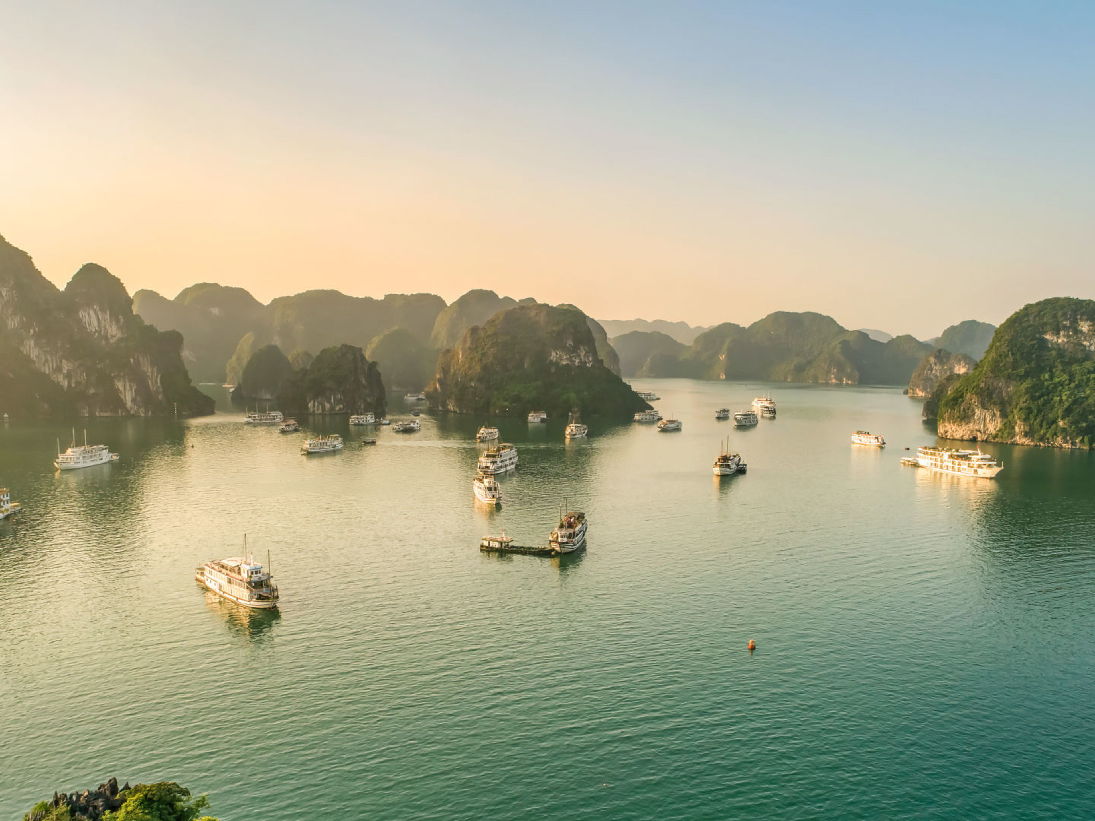 Boote in der Halong-Bucht bei Sonnenuntergang, umgeben von Kalksteinfelsen. Boote in der Halong-Bucht bei Sonnenuntergang, umgeben von Kalksteinfelsen.