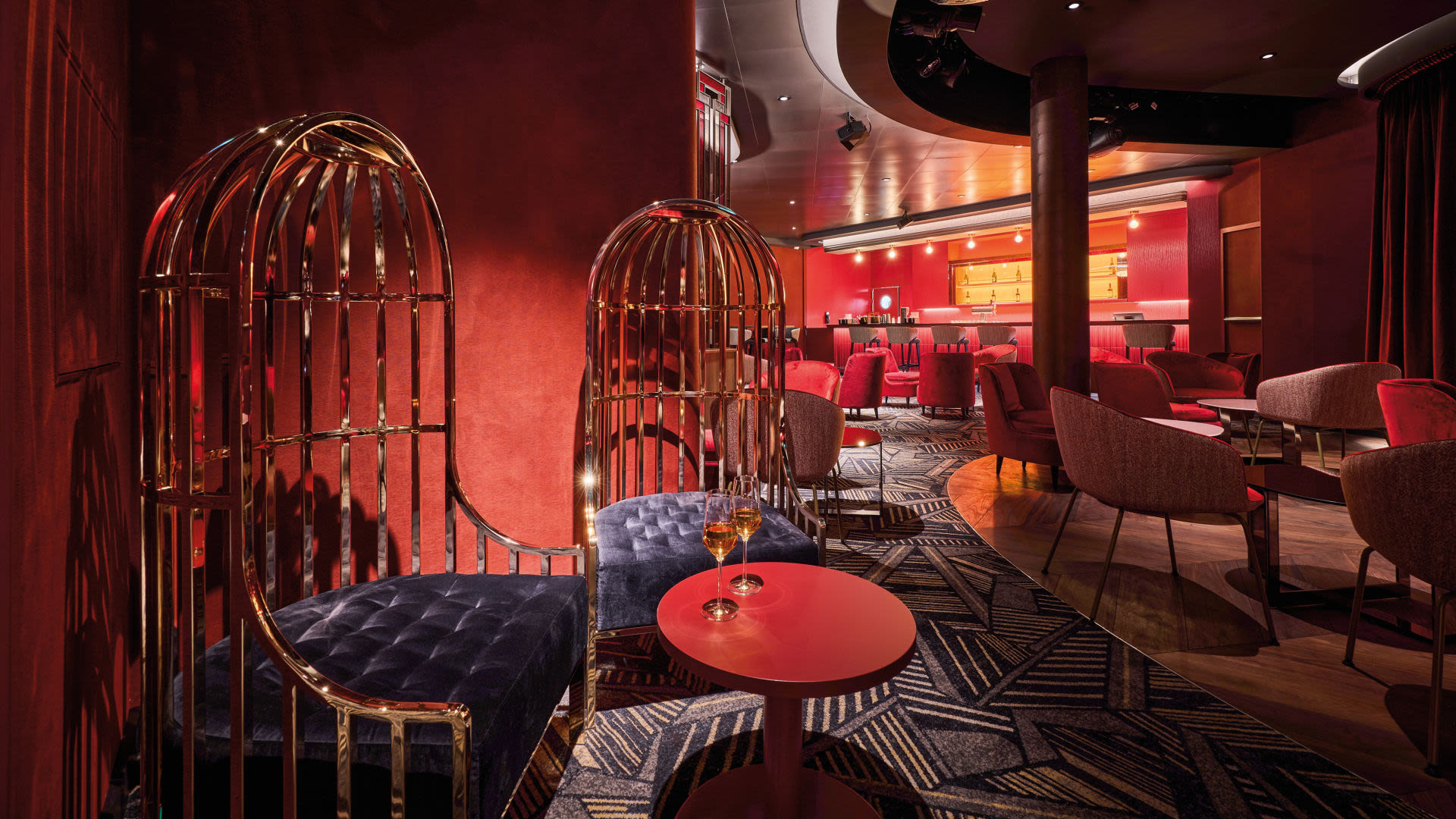 Elegante rote Lounge mit goldenen Käfigstühlen und Bar.