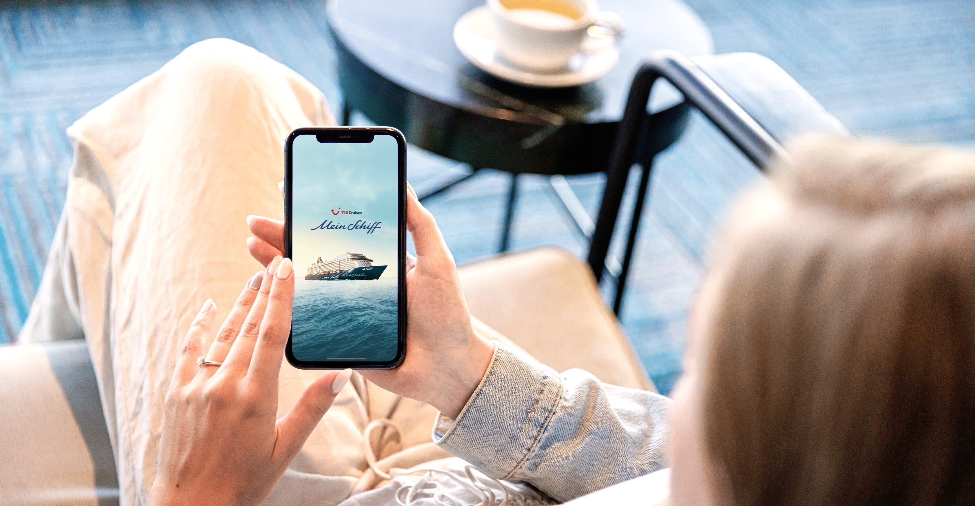 Frau betrachtet Kreuzfahrtschiff der Mein Schiff® Flotte auf Smartphone. Frau betrachtet Kreuzfahrtschiff der Mein Schiff® Flotte auf Smartphone.