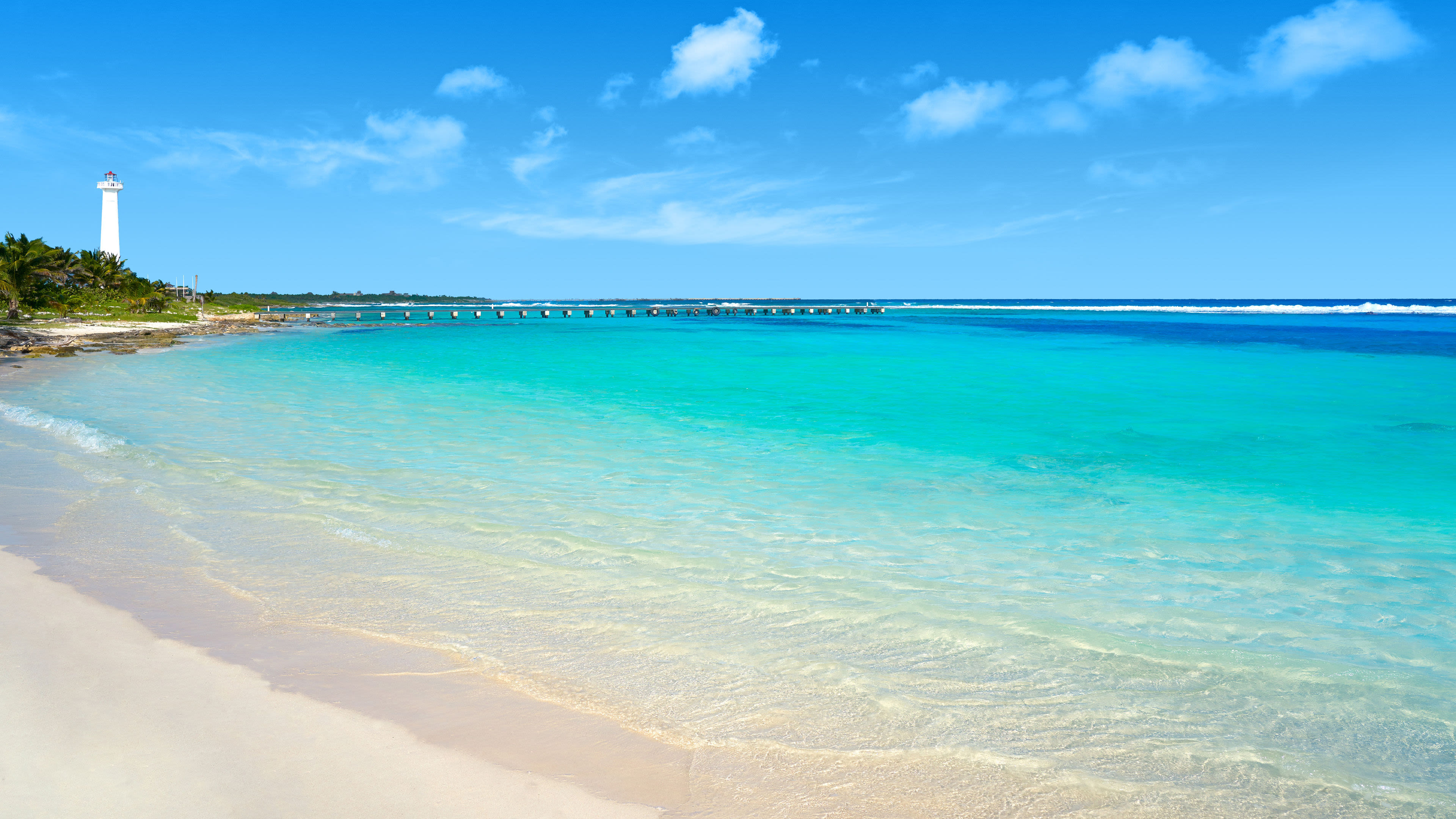 Strand mit türkisfarbenem Wasser, Leuchtturm und blauem Himmel. Strand mit türkisfarbenem Wasser, Leuchtturm und blauem Himmel.