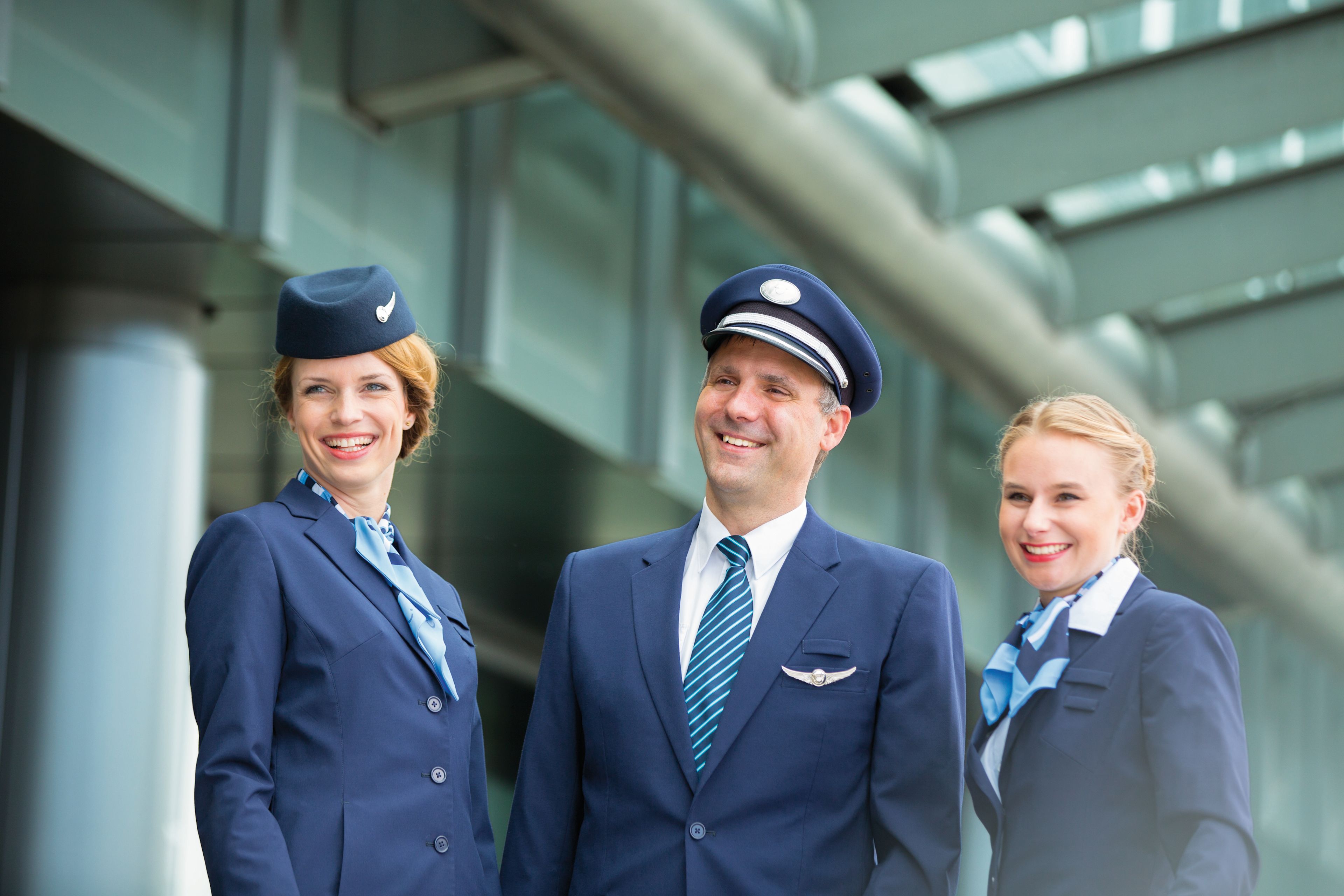 Flugbegleiter und Pilot in blauen Uniformen lächeln. Flugbegleiter und Pilot in blauen Uniformen lächeln.