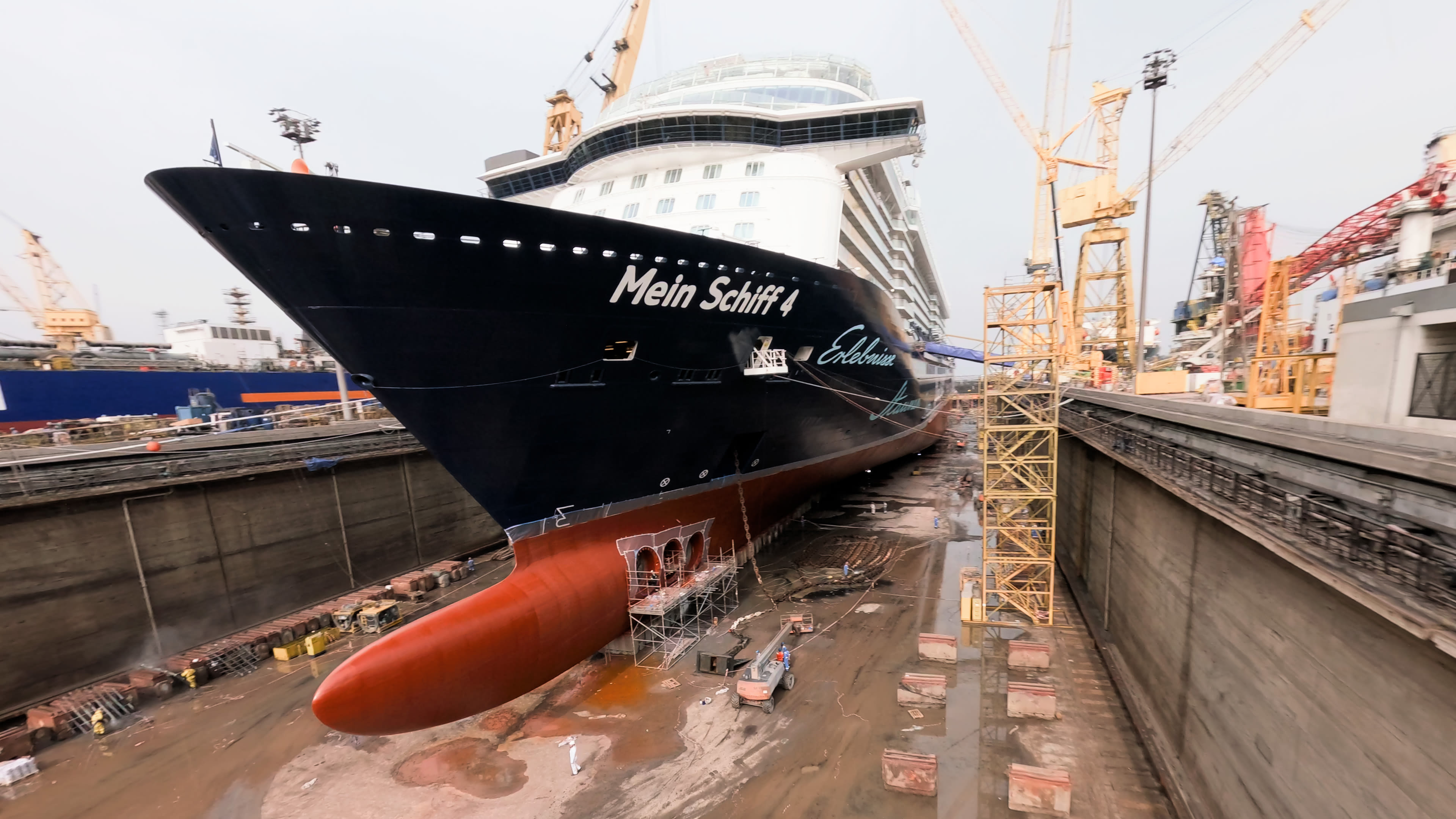 Kreuzfahrtschiff der Mein Schiff® Flotte im Trockendock, umgeben von Kränen. Kreuzfahrtschiff der Mein Schiff® Flotte im Trockendock, umgeben von Kränen.