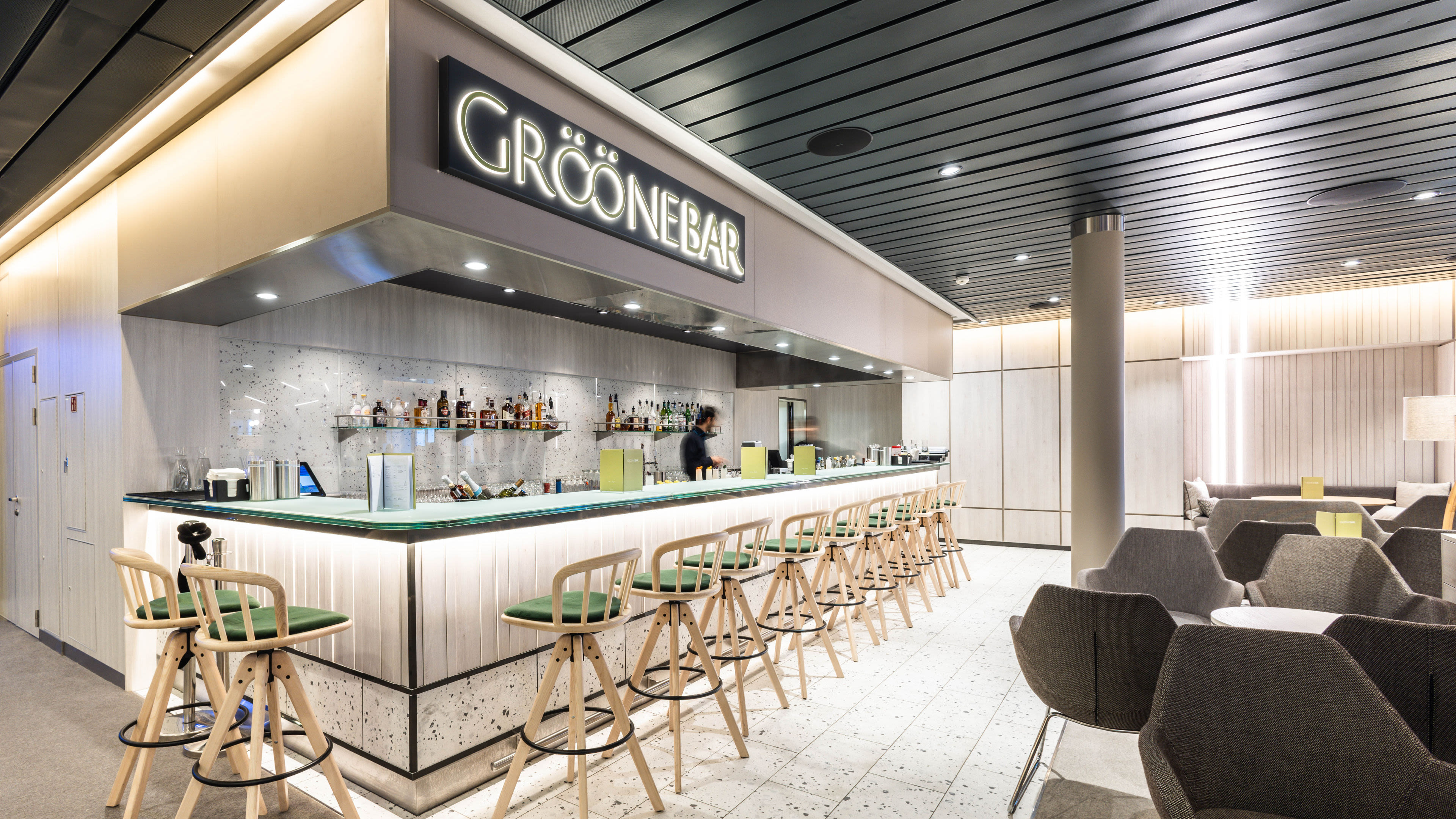 Moderne Bar mit grünen Hockern, beleuchtetem Tresen und gemütlichen Sitzbereichen. Moderne Bar mit grünen Hockern, beleuchtetem Tresen und gemütlichen Sitzbereichen.