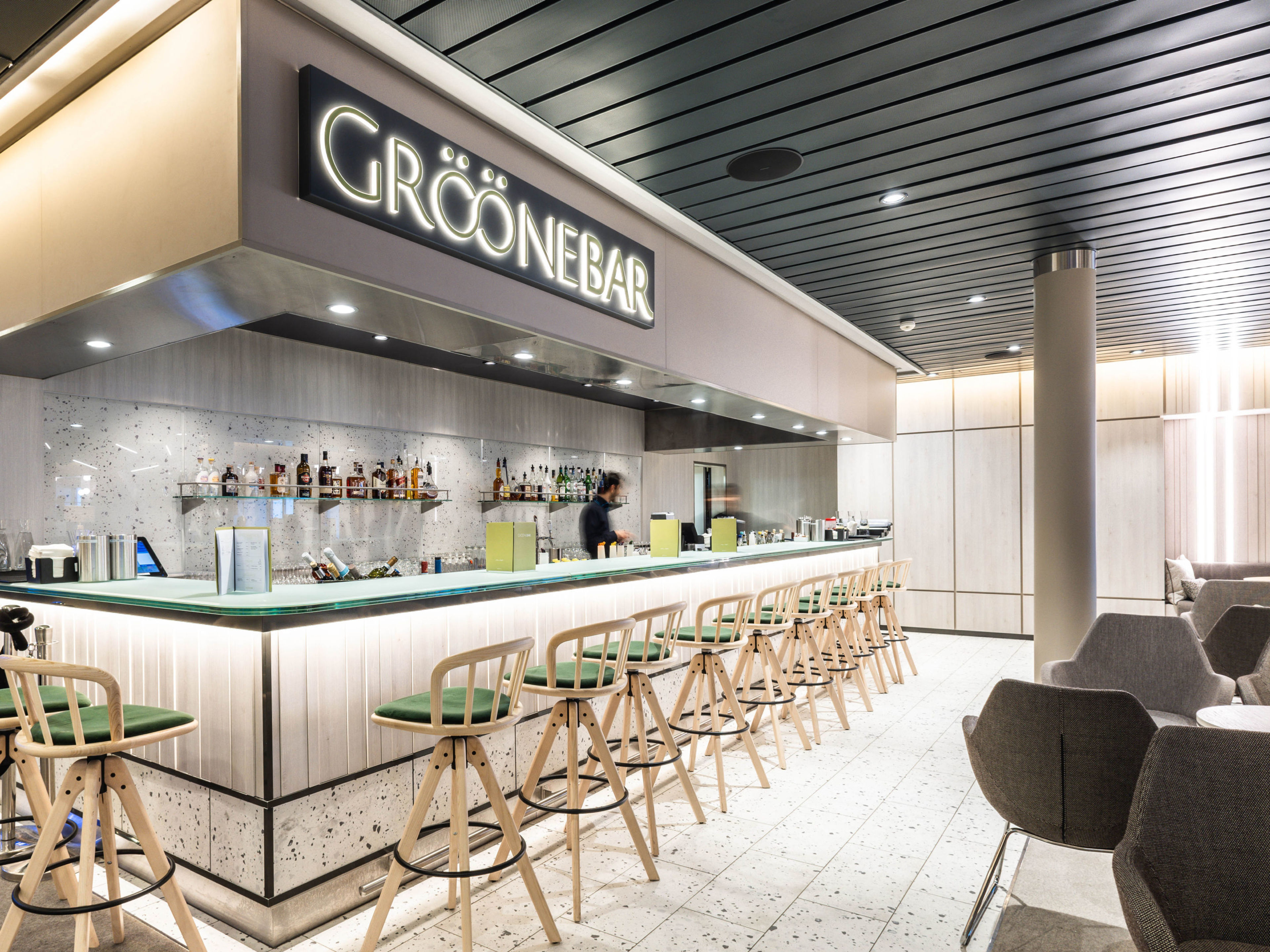 Moderne Bar mit grünen Hockern, beleuchtetem Tresen und gemütlichen Sitzbereichen. Moderne Bar mit grünen Hockern, beleuchtetem Tresen und gemütlichen Sitzbereichen.