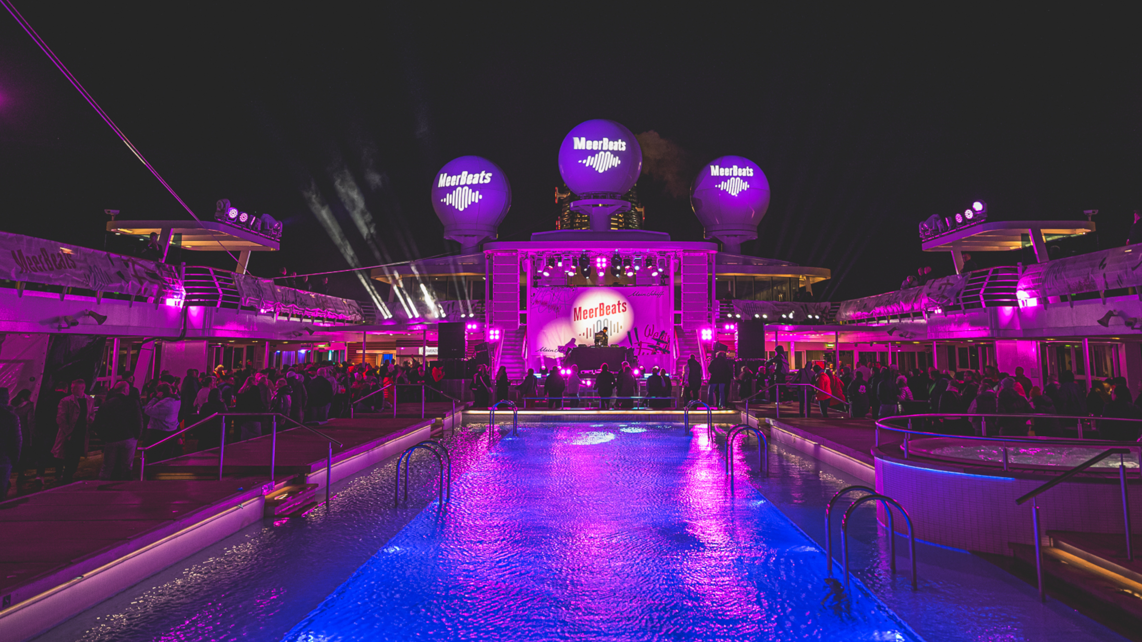 Nachtparty auf Kreuzfahrtschiff der Mein Schiff® Flotte, lila Beleuchtung, Pool, Menschenmenge. Nachtparty auf Kreuzfahrtschiff der Mein Schiff® Flotte, lila Beleuchtung, Pool, Menschenmenge.