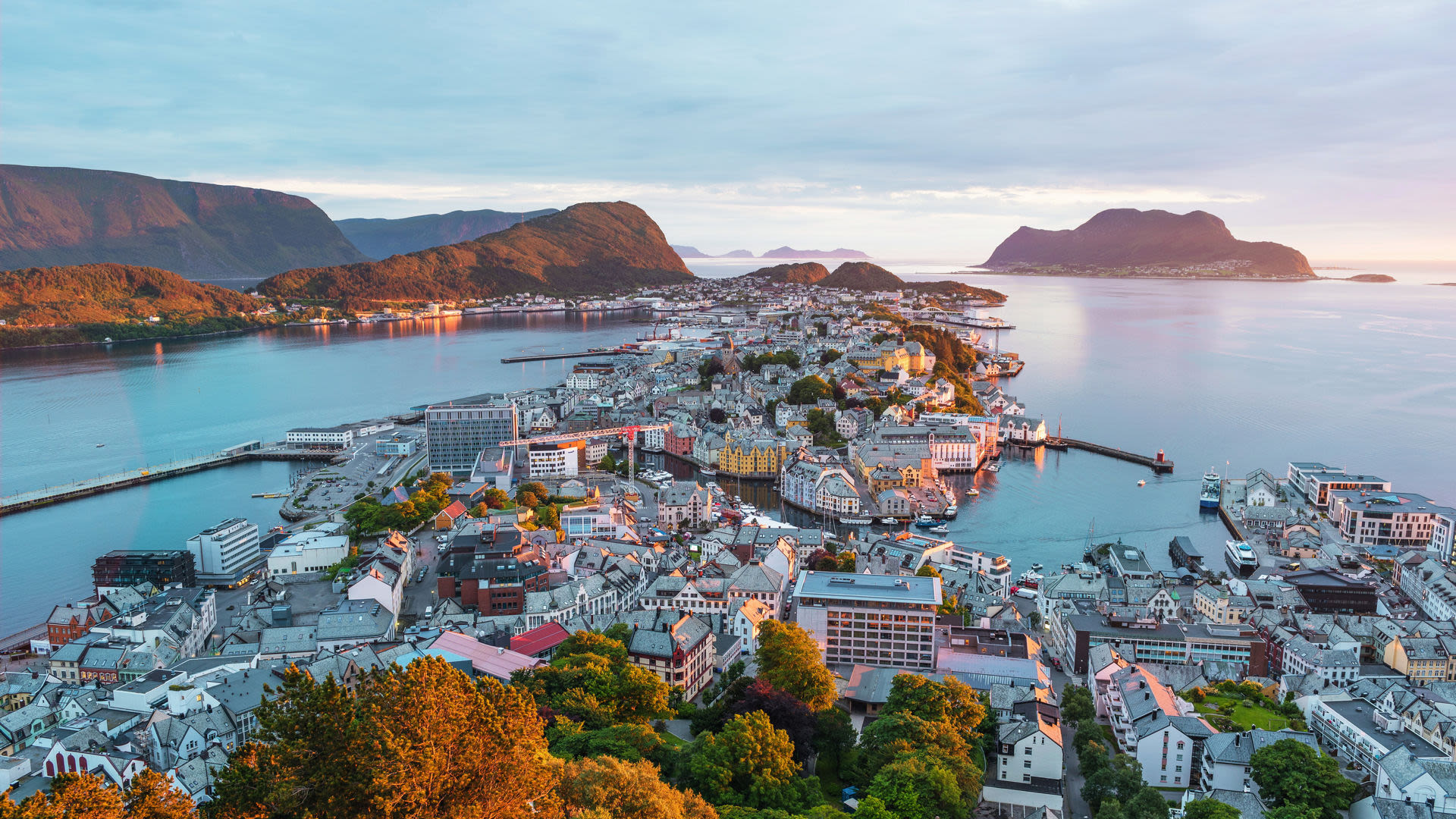 Blick auf Ålesund, Norwegen, bei Sonnenuntergang mit Fjorden und bunten Häusern.