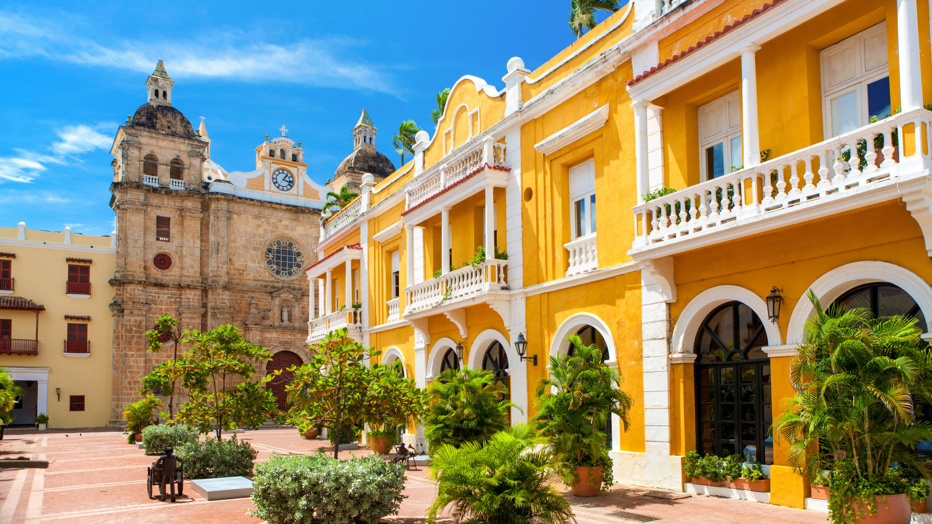 Gelbes Kolonialgebäude und Kirche in Cartagena, blauer Himmel.