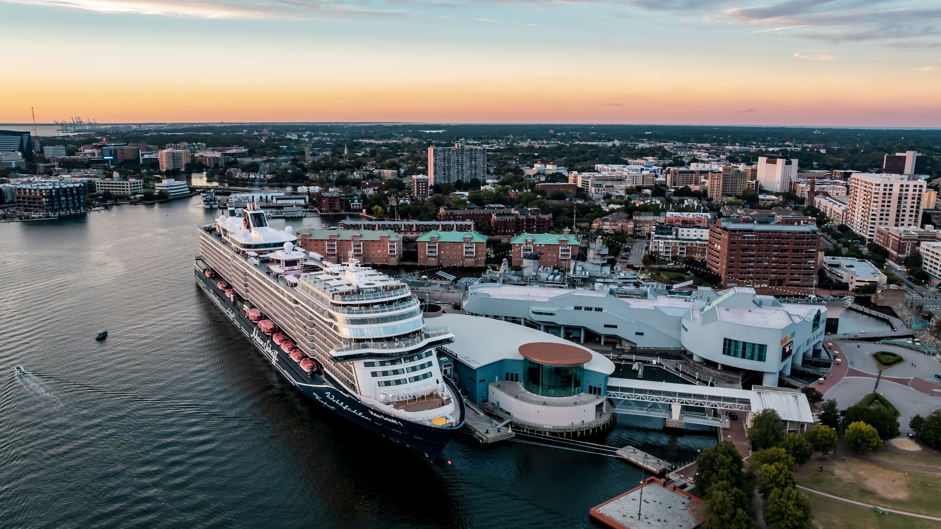 Kreuzfahrtschiff der Mein Schiff® Flotte im Hafen bei Sonnenuntergang, Stadt im Hintergrund. Kreuzfahrtschiff der Mein Schiff® Flotte im Hafen bei Sonnenuntergang, Stadt im Hintergrund.