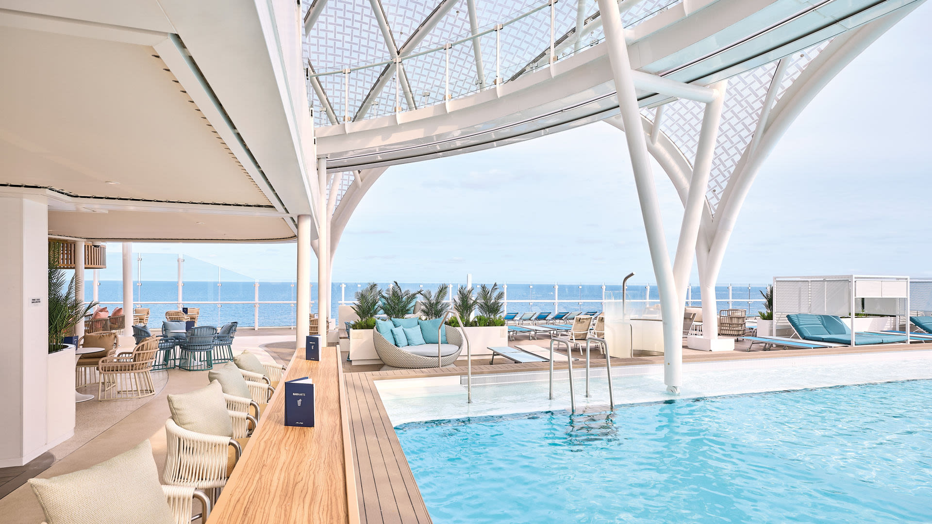 Pooldeck auf Kreuzfahrtschiff mit Meerblick, moderne Möbel, helle Farben.