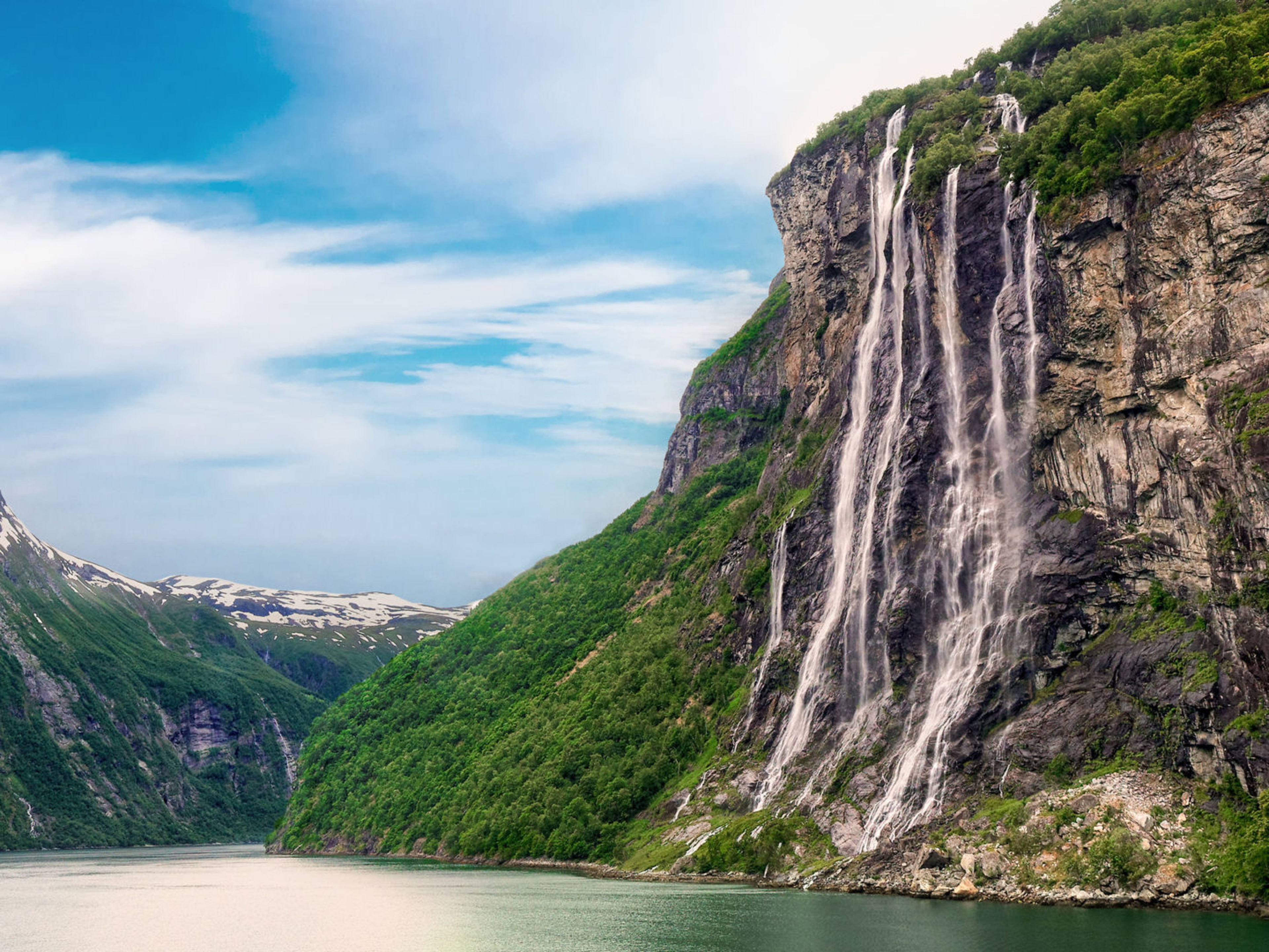 Wasserfall im Geirangerfjord, Norwegen, mit grünen Bergen und blauem Himmel. Wasserfall im Geirangerfjord, Norwegen, mit grünen Bergen und blauem Himmel.