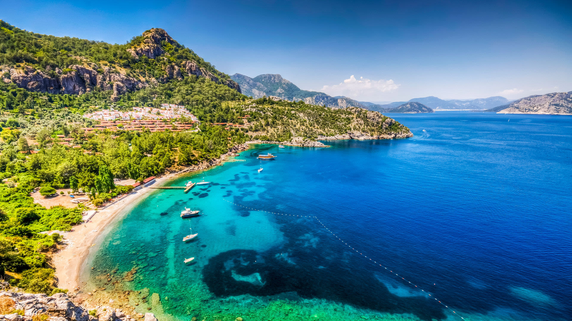 Türkische Küste mit blauem Meer, grünen Hügeln und Booten. Türkische Küste mit blauem Meer, grünen Hügeln und Booten.