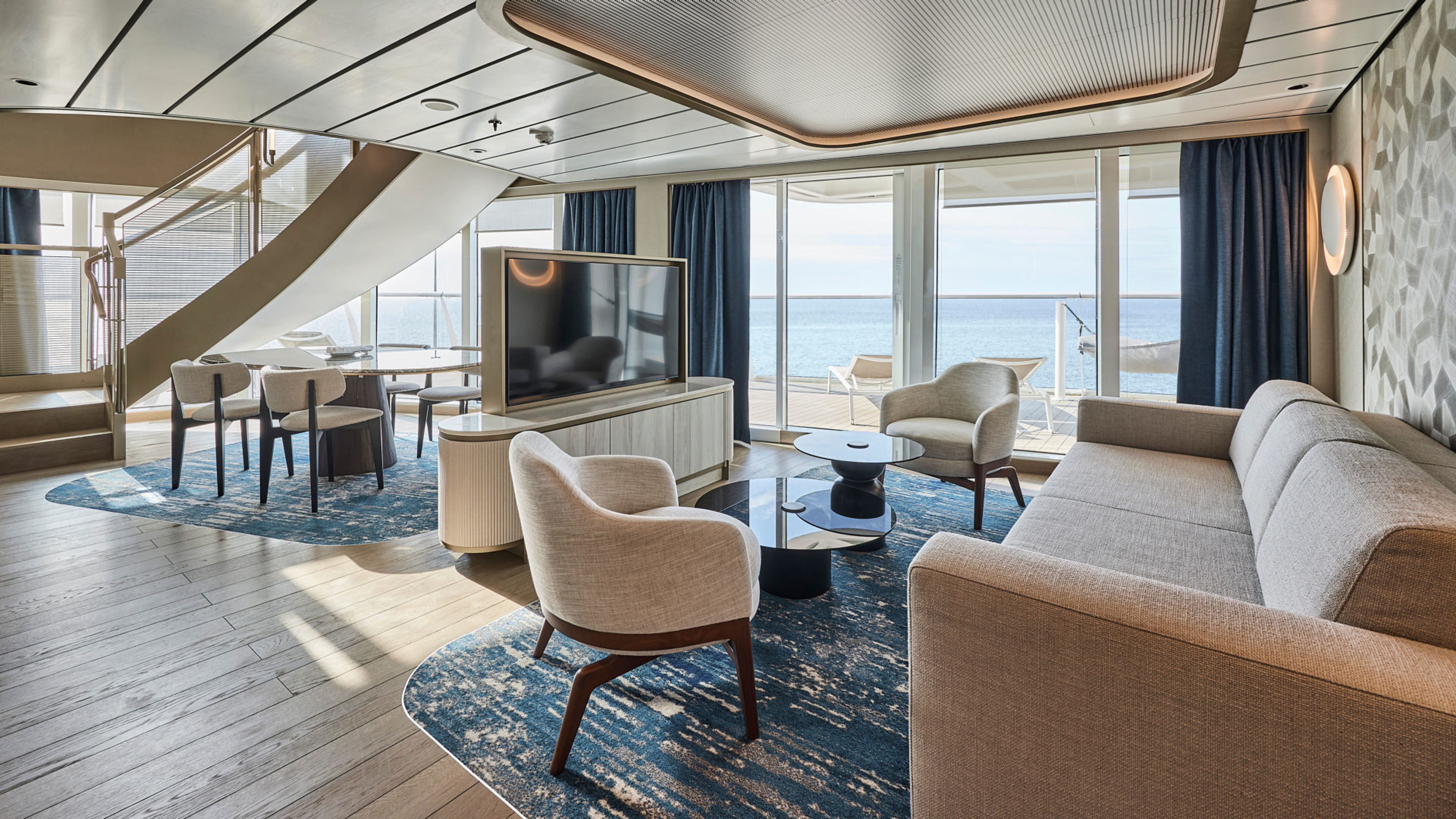 Modernes Wohnzimmer auf Kreuzfahrtschiff mit Meerblick, blauer Teppich, helle Möbel. Modernes Wohnzimmer auf Kreuzfahrtschiff mit Meerblick, blauer Teppich, helle Möbel.