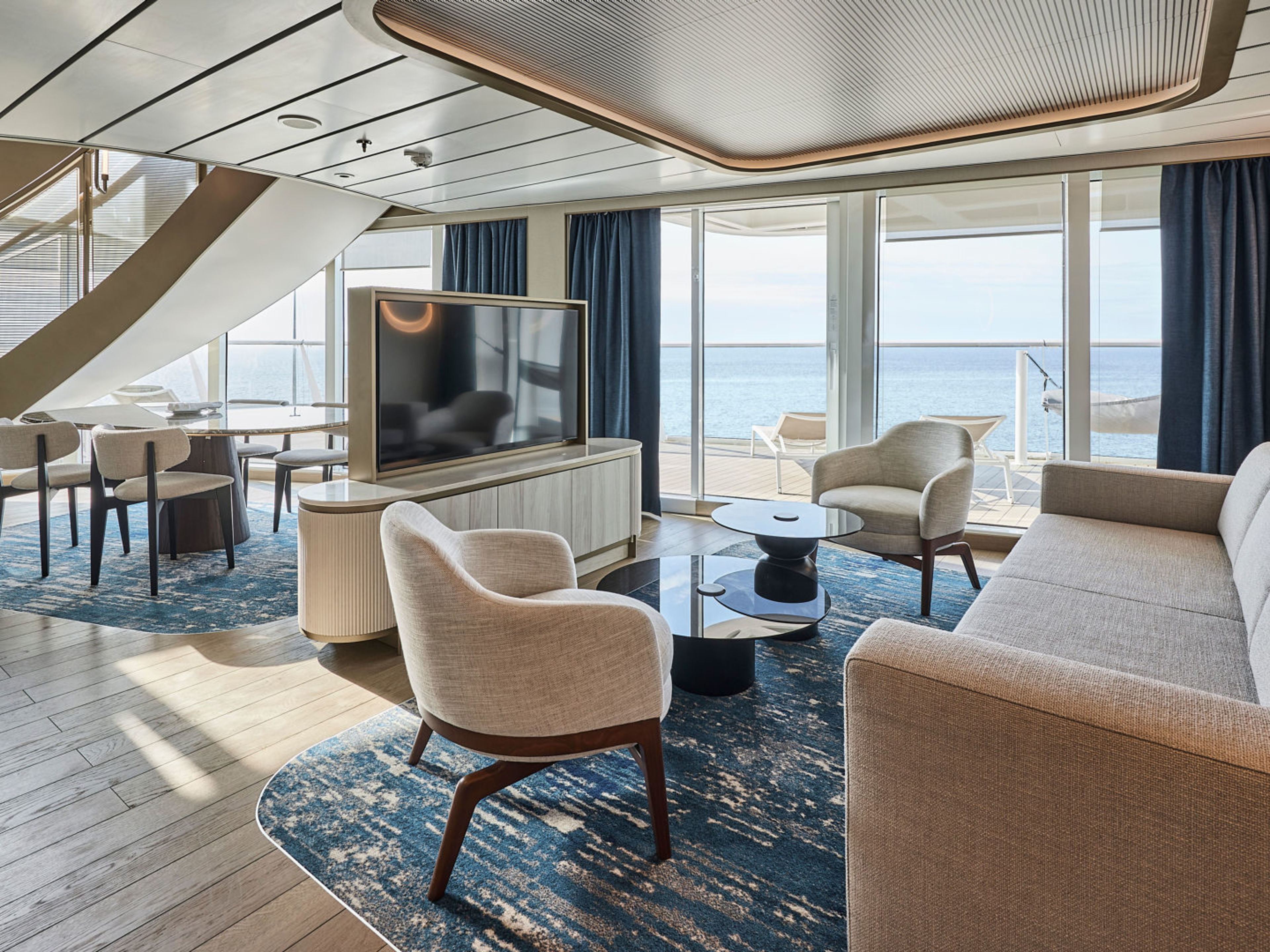 Modernes Wohnzimmer auf Kreuzfahrtschiff mit Meerblick, blauer Teppich, helle Möbel. Modernes Wohnzimmer auf Kreuzfahrtschiff mit Meerblick, blauer Teppich, helle Möbel.