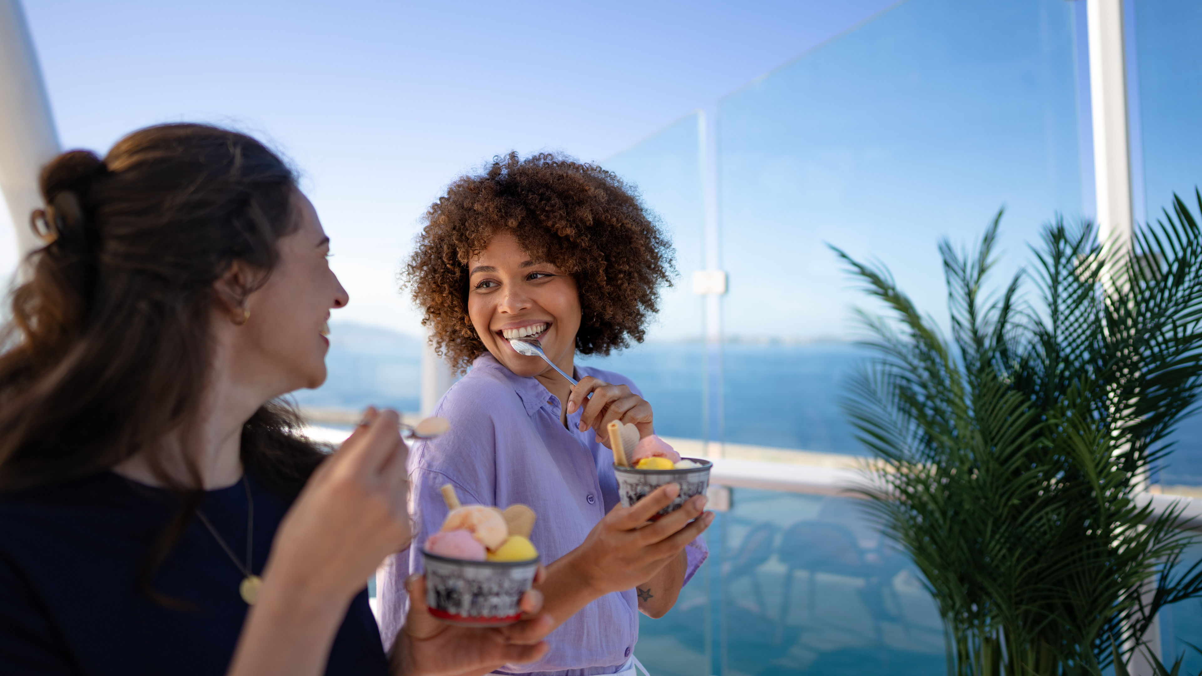 Two women enjoy ice cream with a view of the sea