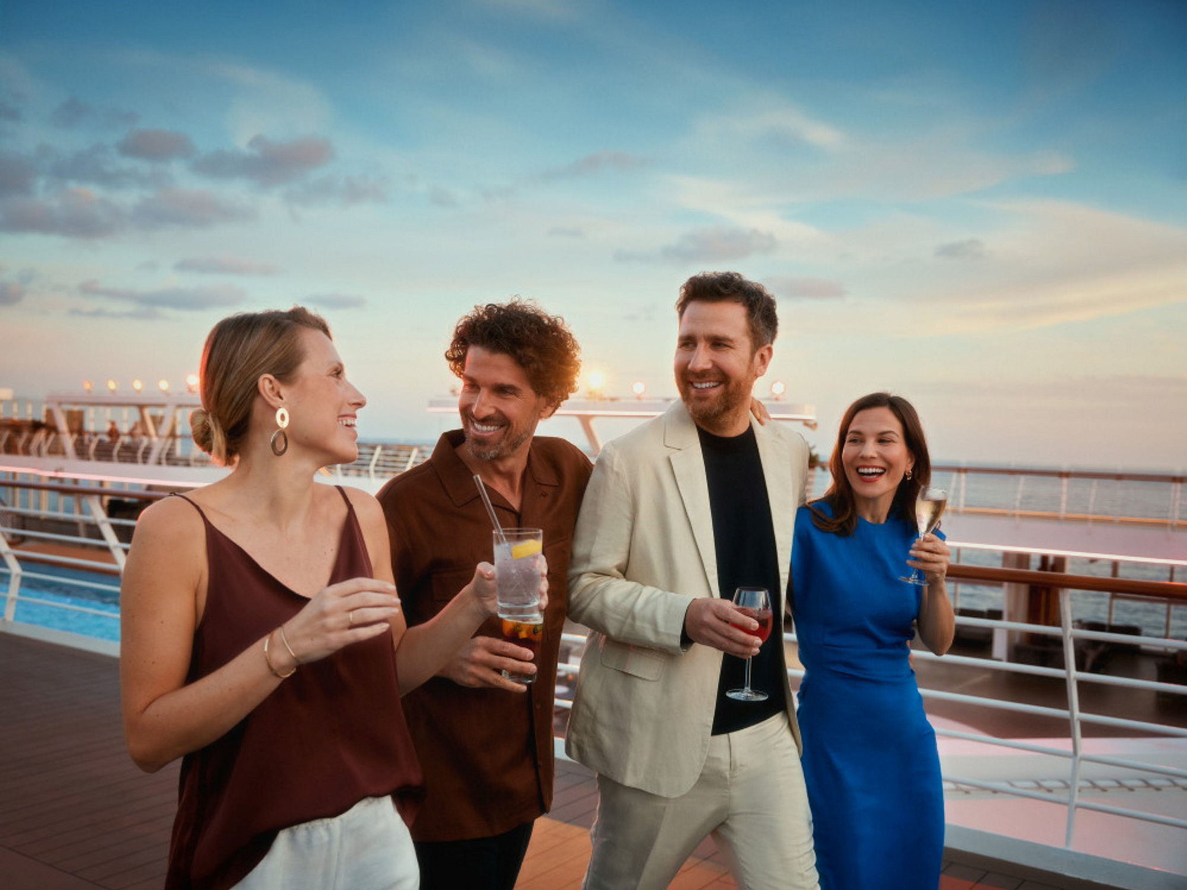 Vier Personen lachen auf einem Kreuzfahrtschiff der Mein Schiff® Flotte bei Sonnenuntergang. Vier Personen lachen auf einem Kreuzfahrtschiff der Mein Schiff® Flotte bei Sonnenuntergang.