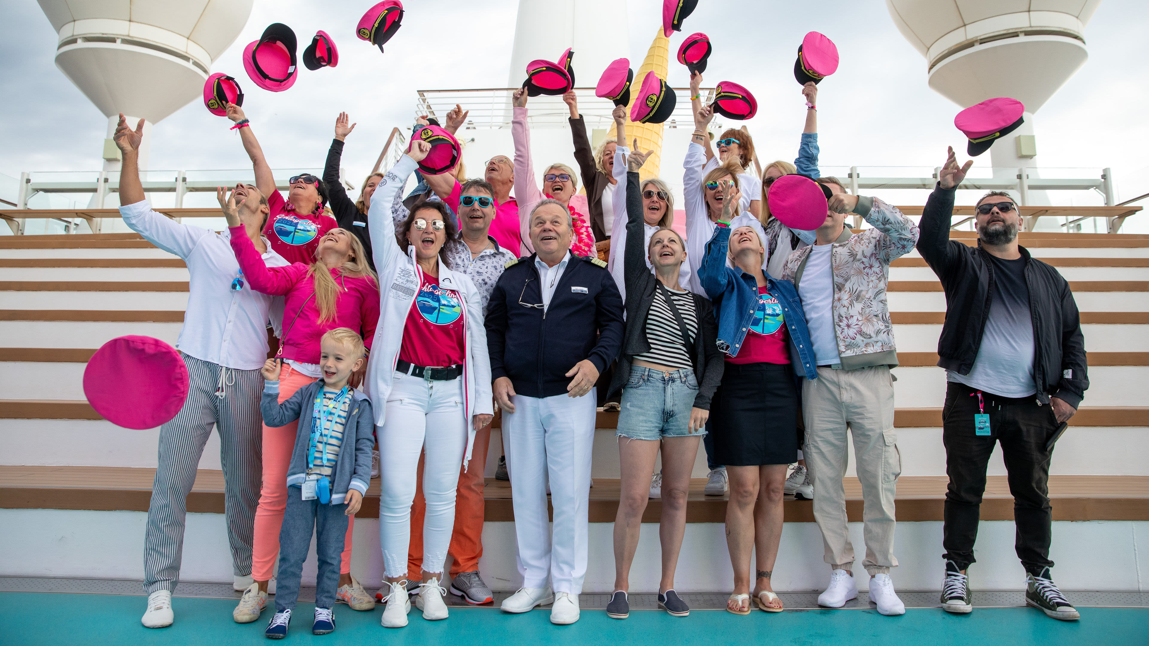 Gruppe wirft pinke Hüte in die Luft auf Kreuzfahrtschiff. Gruppe wirft pinke Hüte in die Luft auf Kreuzfahrtschiff.