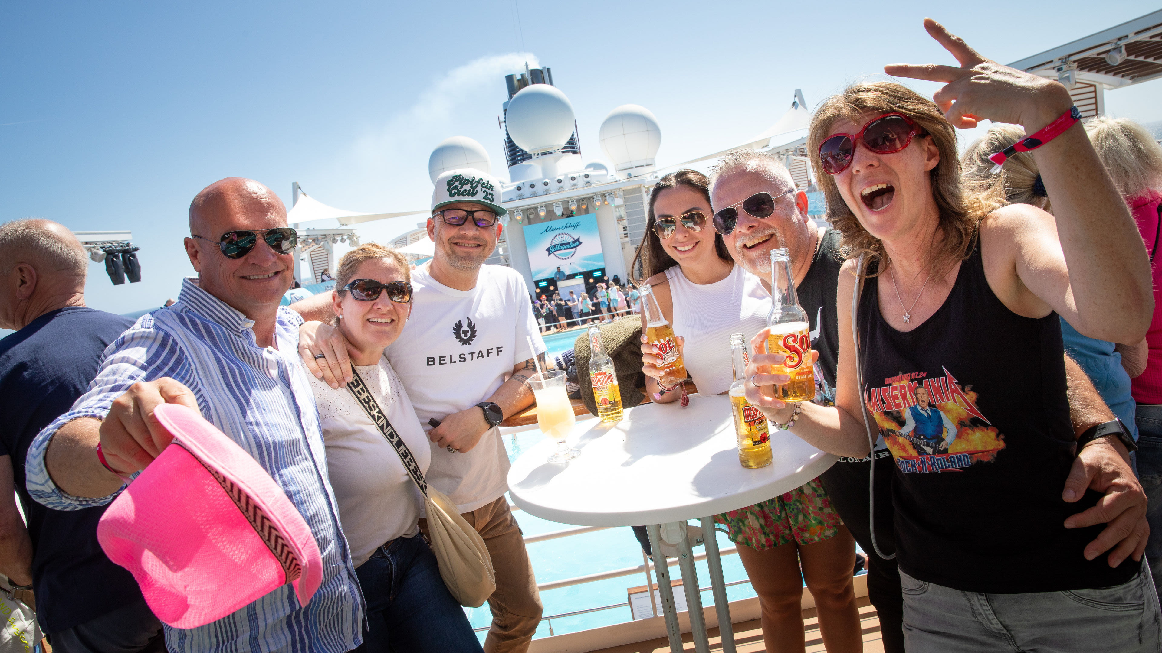 Gruppe feiert auf Kreuzfahrtschiff der Mein Schiff® Flotte bei Sonnenschein.