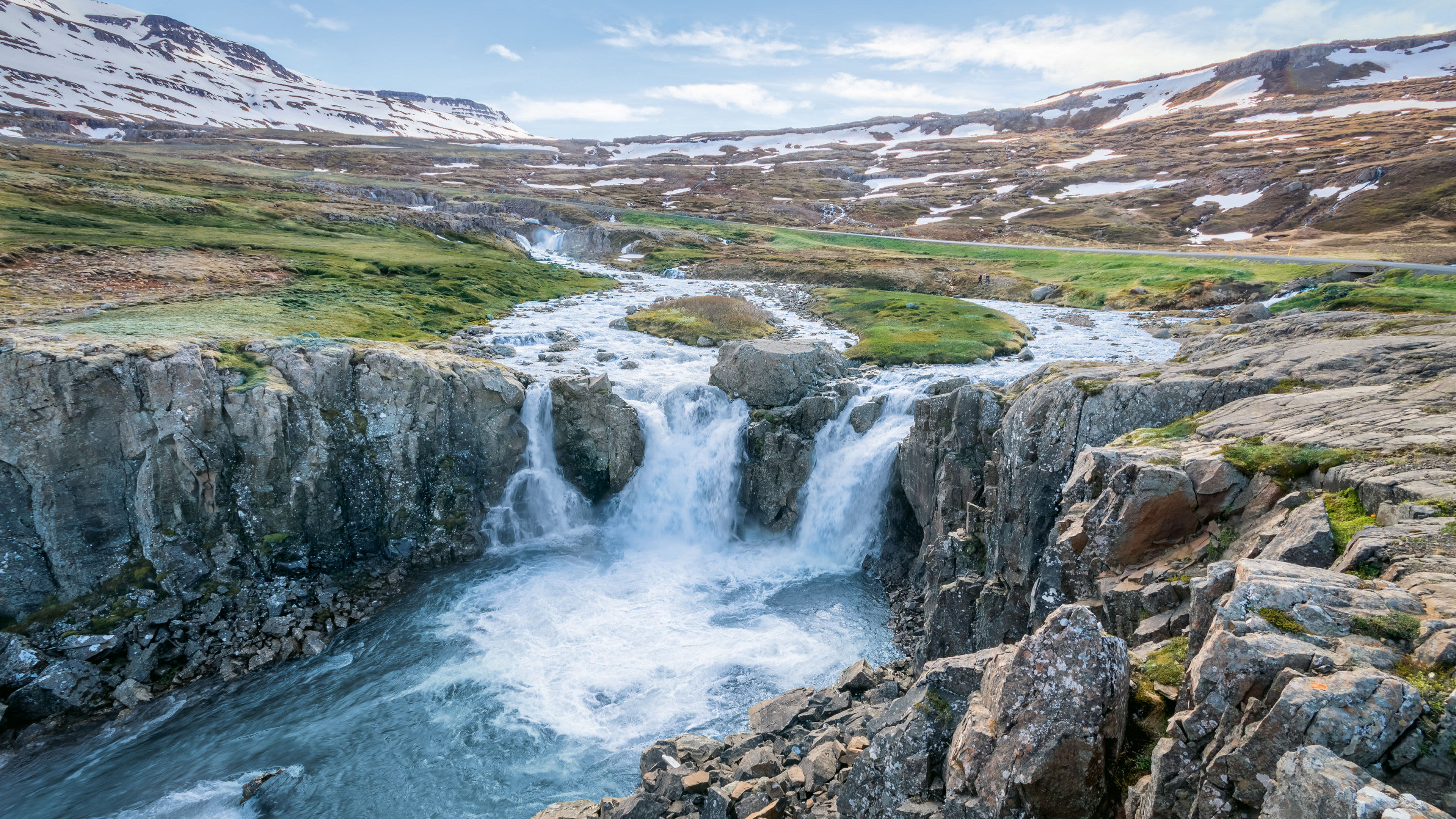 Wasserfall in isländischer Landschaft mit schneebedeckten Bergen und grünem Moos. Wasserfall in isländischer Landschaft mit schneebedeckten Bergen und grünem Moos.