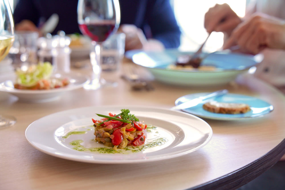 Gourmetgericht auf weißem Teller, Glas Rotwein, gedeckter Tisch. Gourmetgericht auf weißem Teller, Glas Rotwein, gedeckter Tisch.