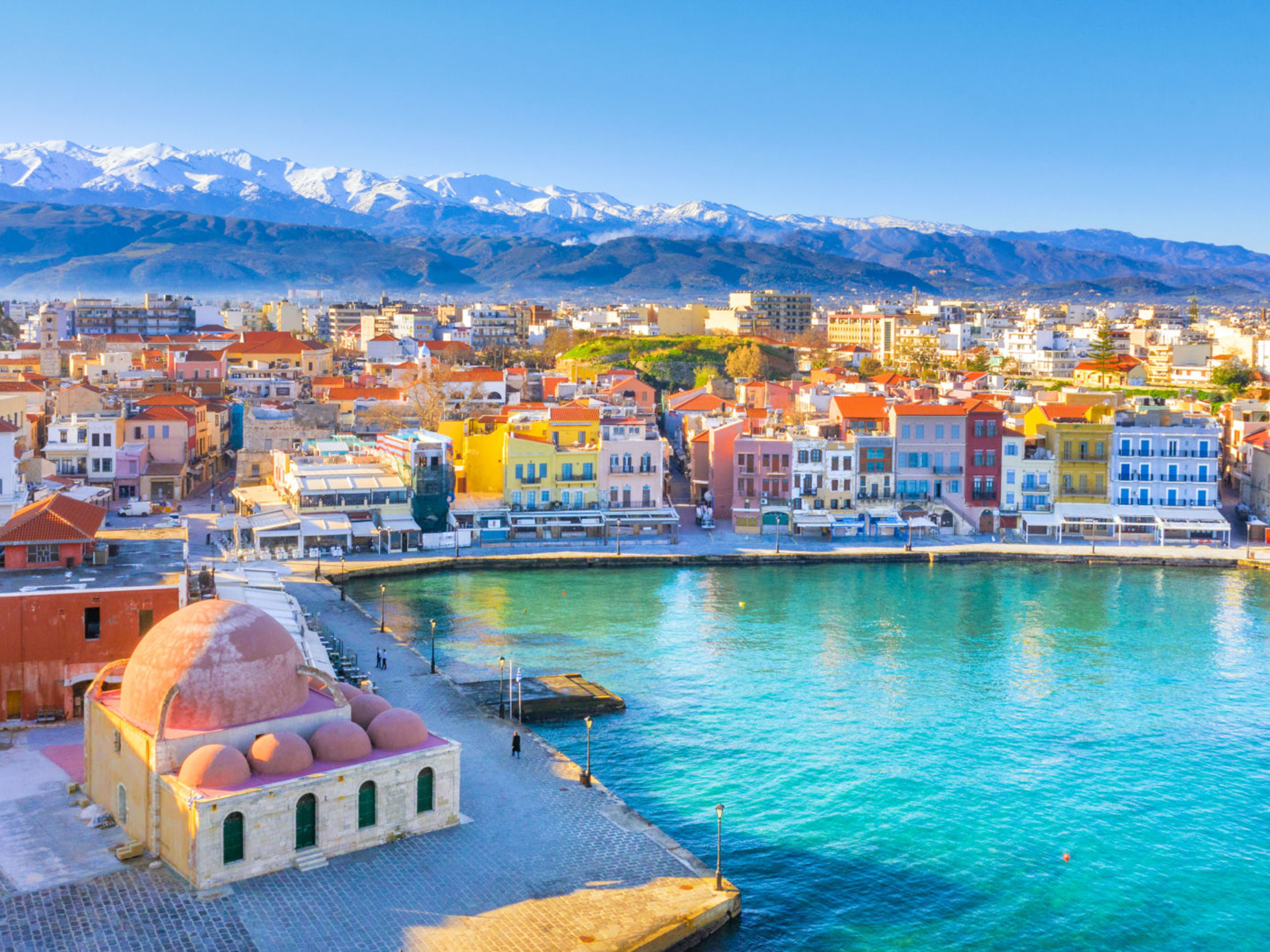 Bunte Häuser am Hafen von Chania, Kreta, mit schneebedeckten Bergen im Hintergrund. Bunte Häuser am Hafen von Chania, Kreta, mit schneebedeckten Bergen im Hintergrund.