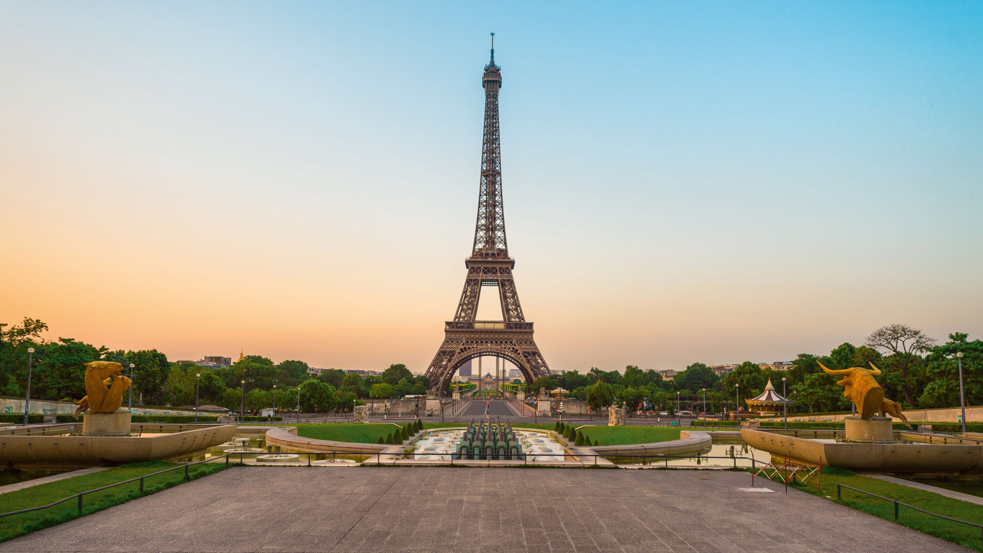 Eiffelturm bei Sonnenuntergang, Paris, mit Springbrunnen und Bäumen.