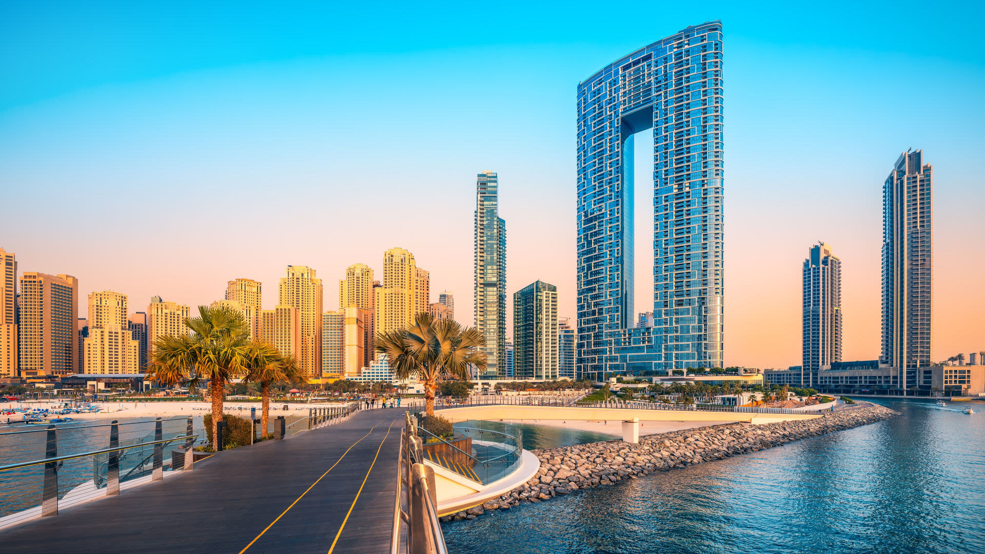 Dubai Marina bei Sonnenuntergang, moderne Wolkenkratzer, Palmen, Promenade.