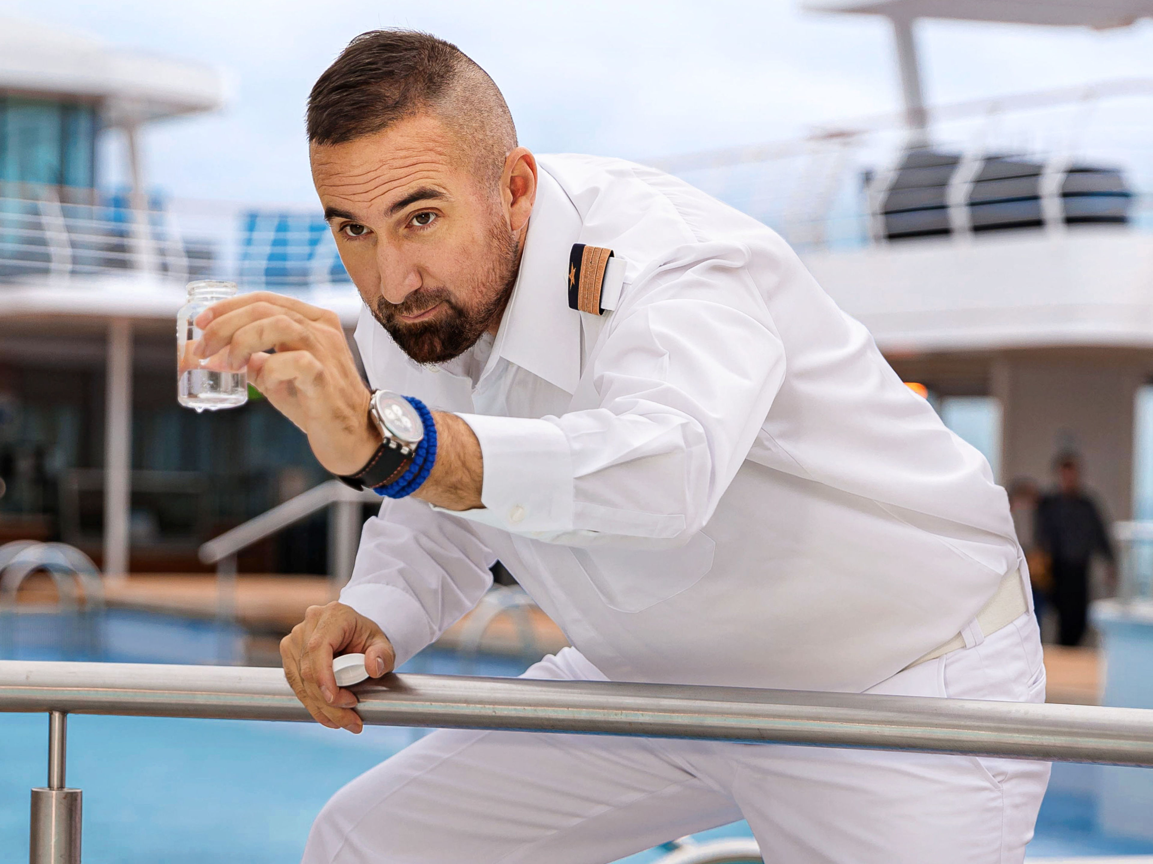 Mann in weißer Uniform prüft Wasser auf Kreuzfahrtschiff. Mann in weißer Uniform prüft Wasser auf Kreuzfahrtschiff.