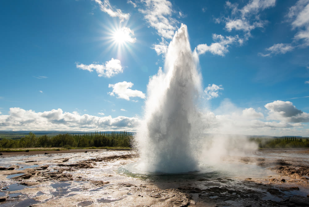 Geysir-Ausbruch unter blauem Himmel mit Sonnenschein. Geysir-Ausbruch unter blauem Himmel mit Sonnenschein.