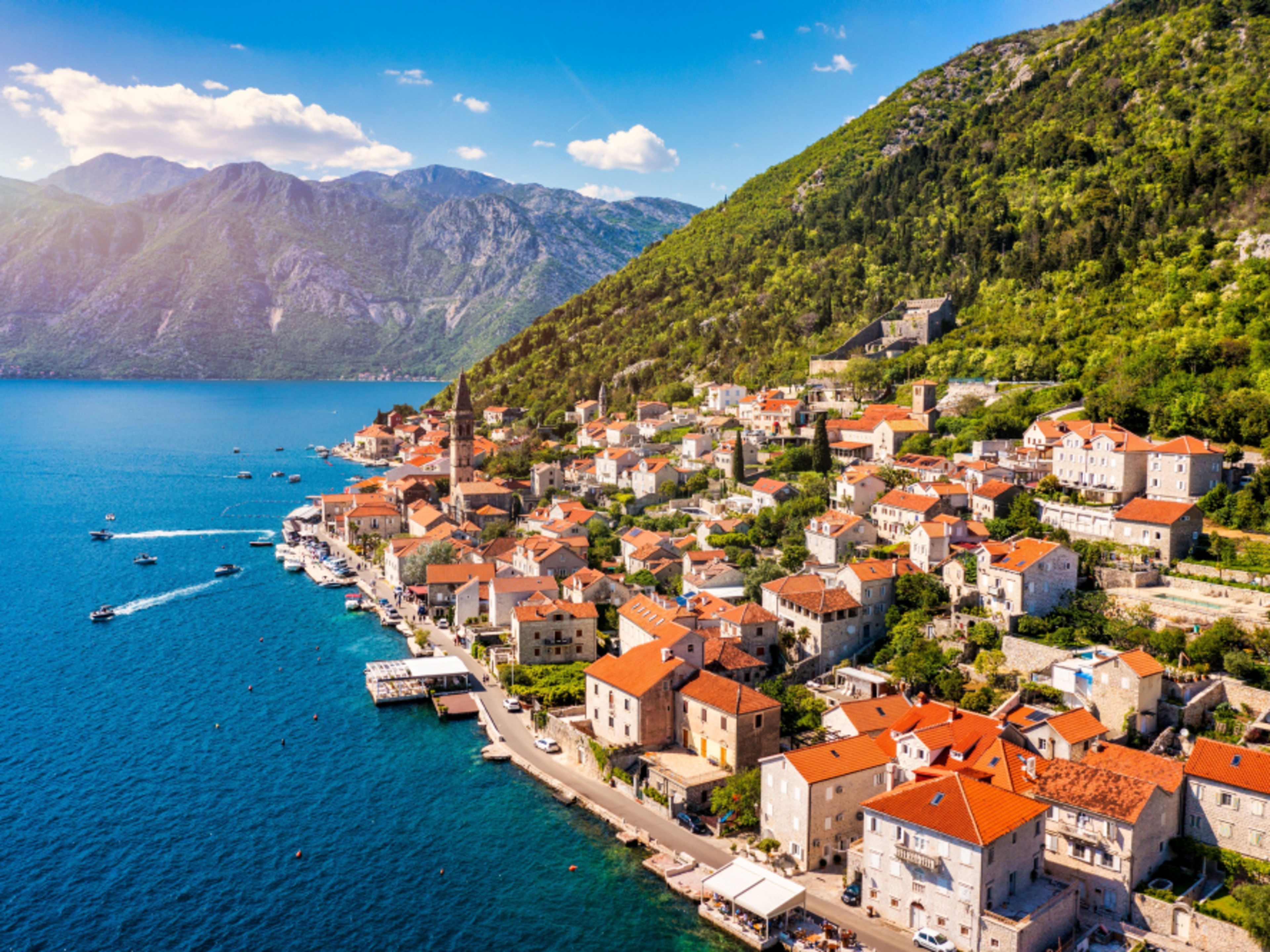 Küstenstadt Perast, Montenegro, mit roten Dächern und Bergen im Hintergrund. Küstenstadt Perast, Montenegro, mit roten Dächern und Bergen im Hintergrund.