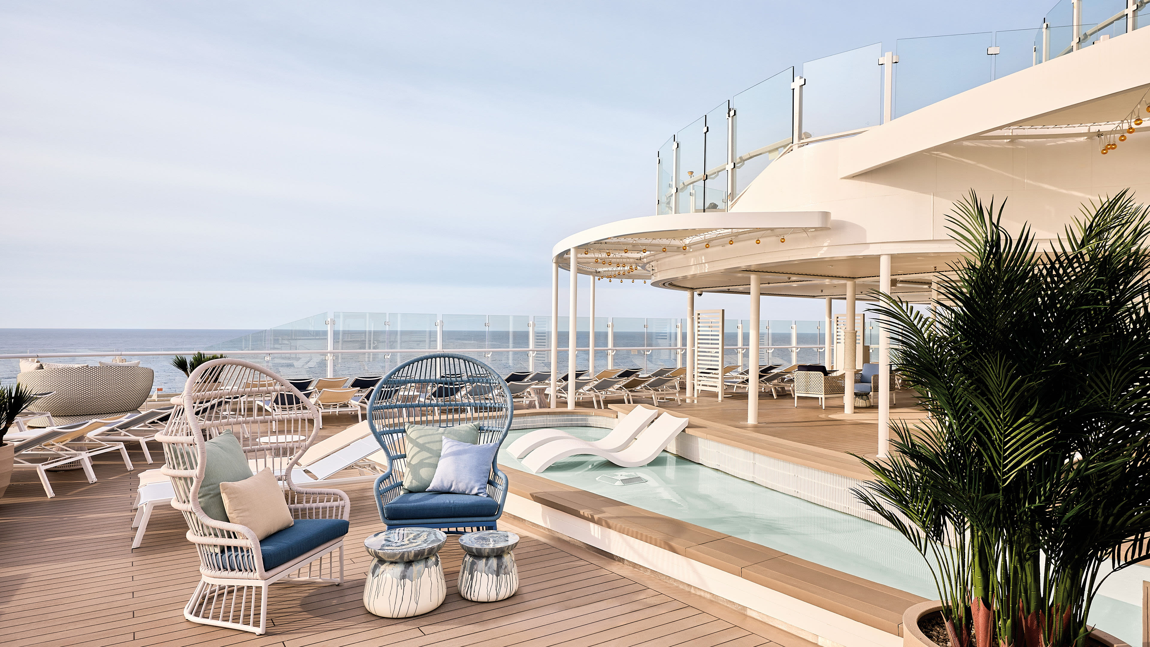 Sonnendeck mit Pool und Liegestühlen auf Kreuzfahrtschiff der Mein Schiff® Flotte.