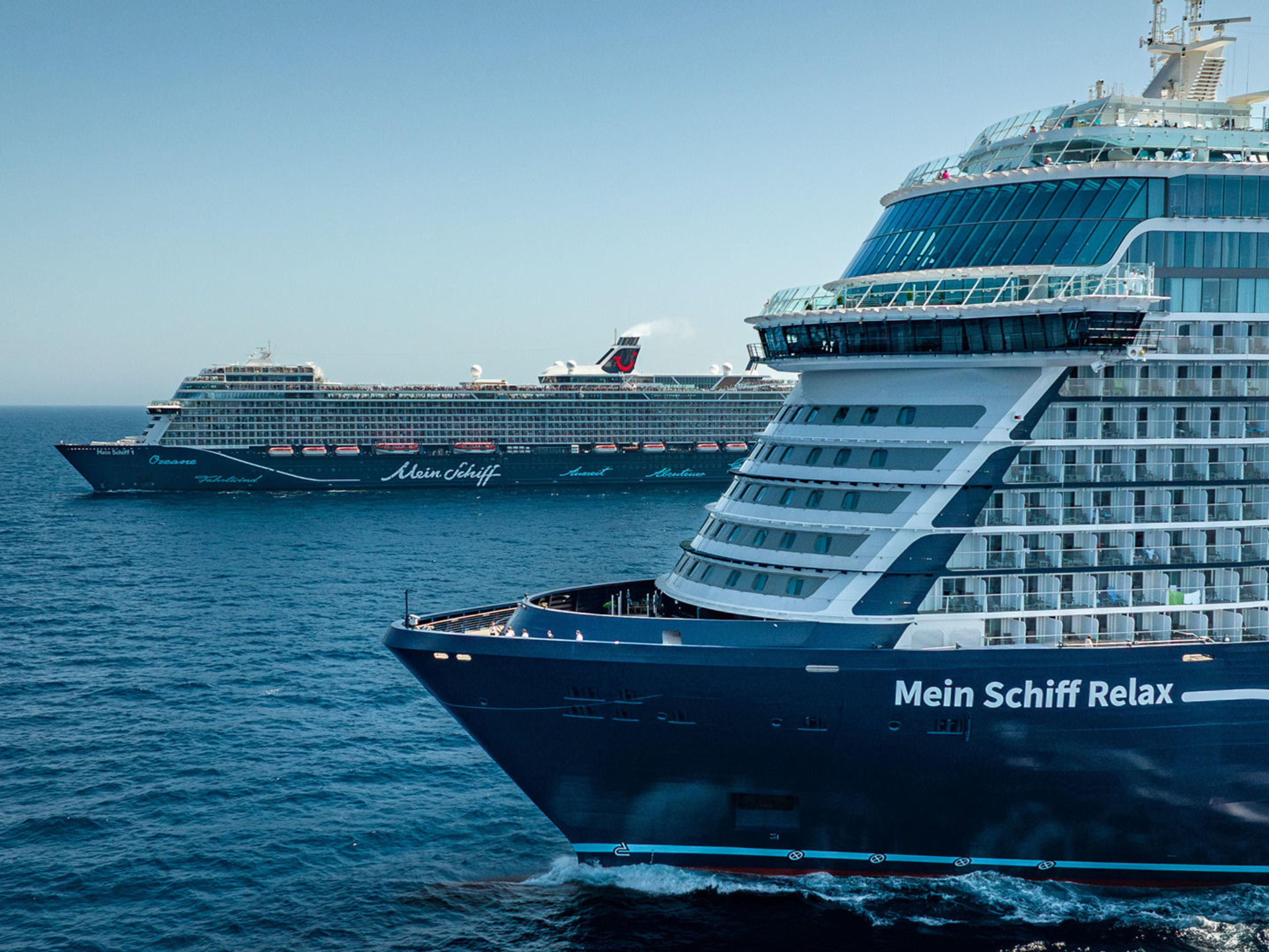 Zwei Kreuzfahrtschiffe der Mein Schiff® Flotte auf offenem Meer. Zwei Kreuzfahrtschiffe der Mein Schiff® Flotte auf offenem Meer.